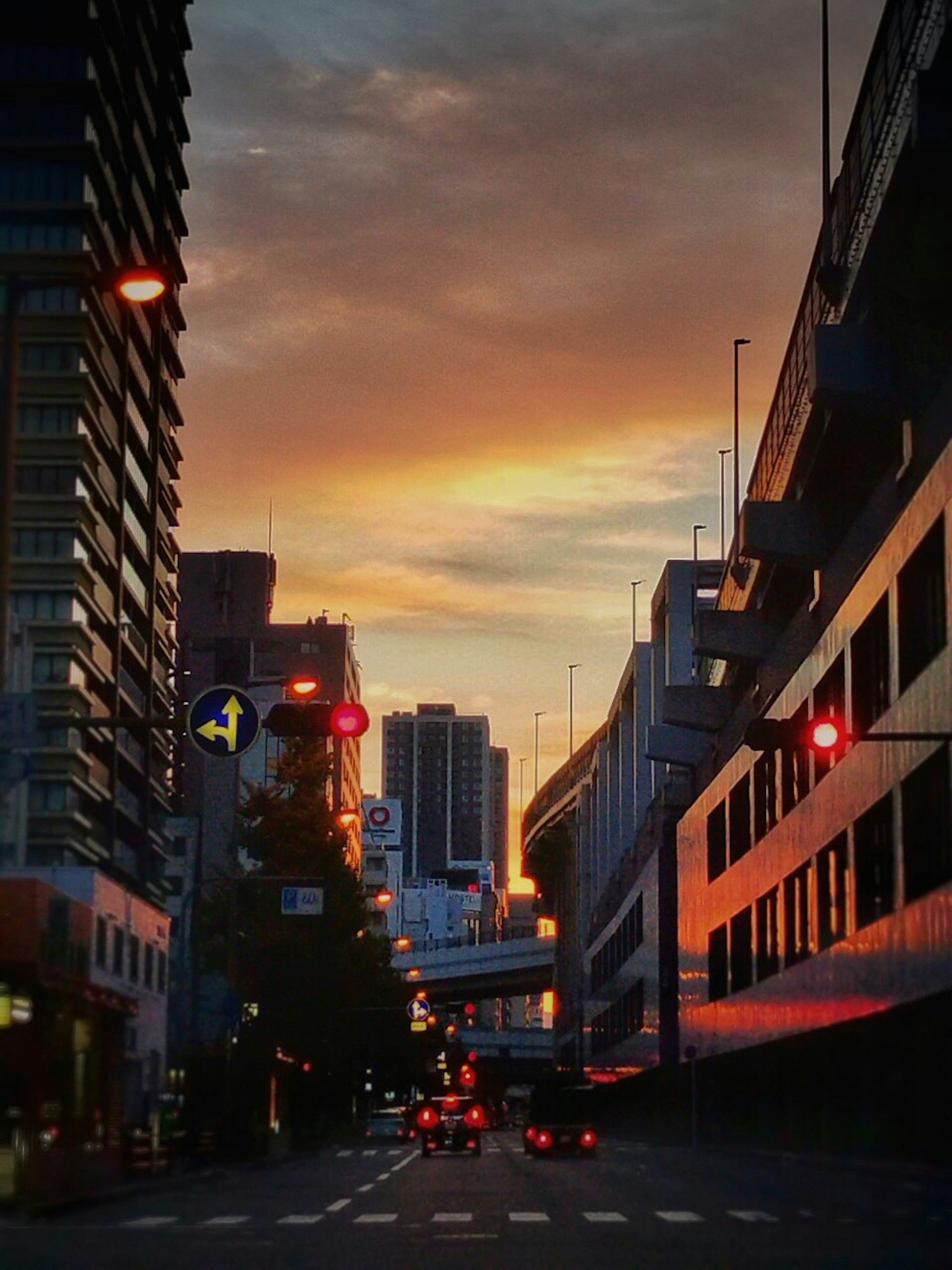 Urban street at sunset with cars and buildings