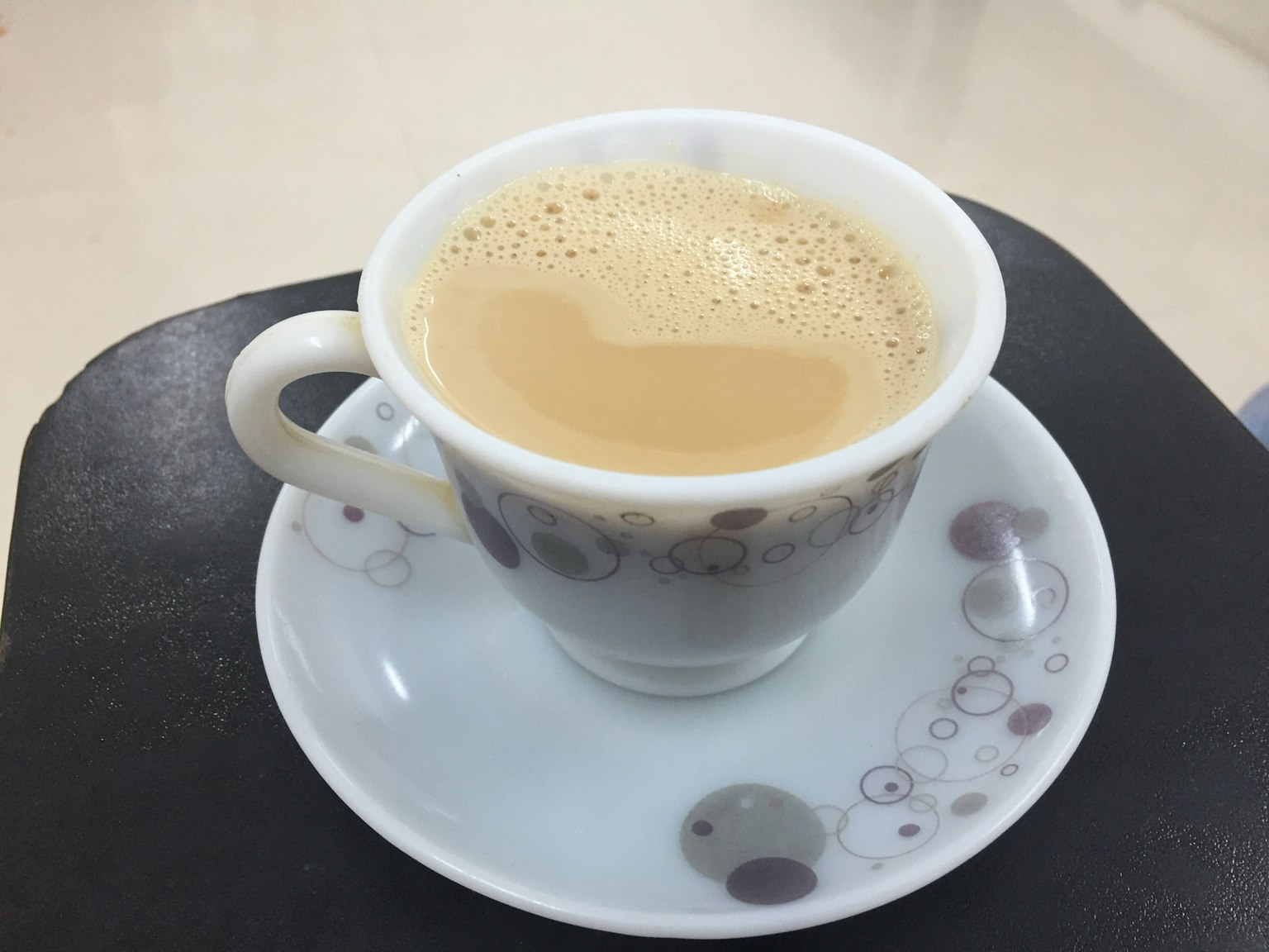Kopi krim dalam cangkir putih dengan piring