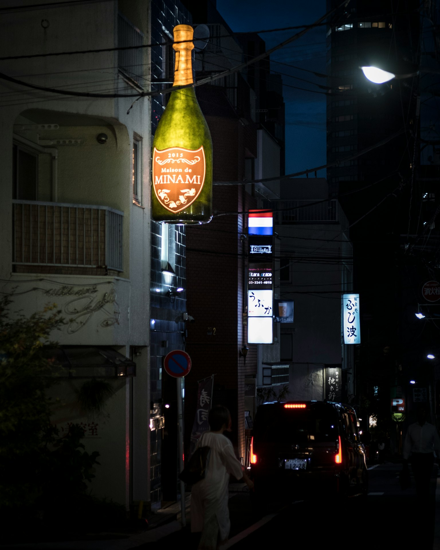 夜の街角にあるシャンパンの看板と通行人