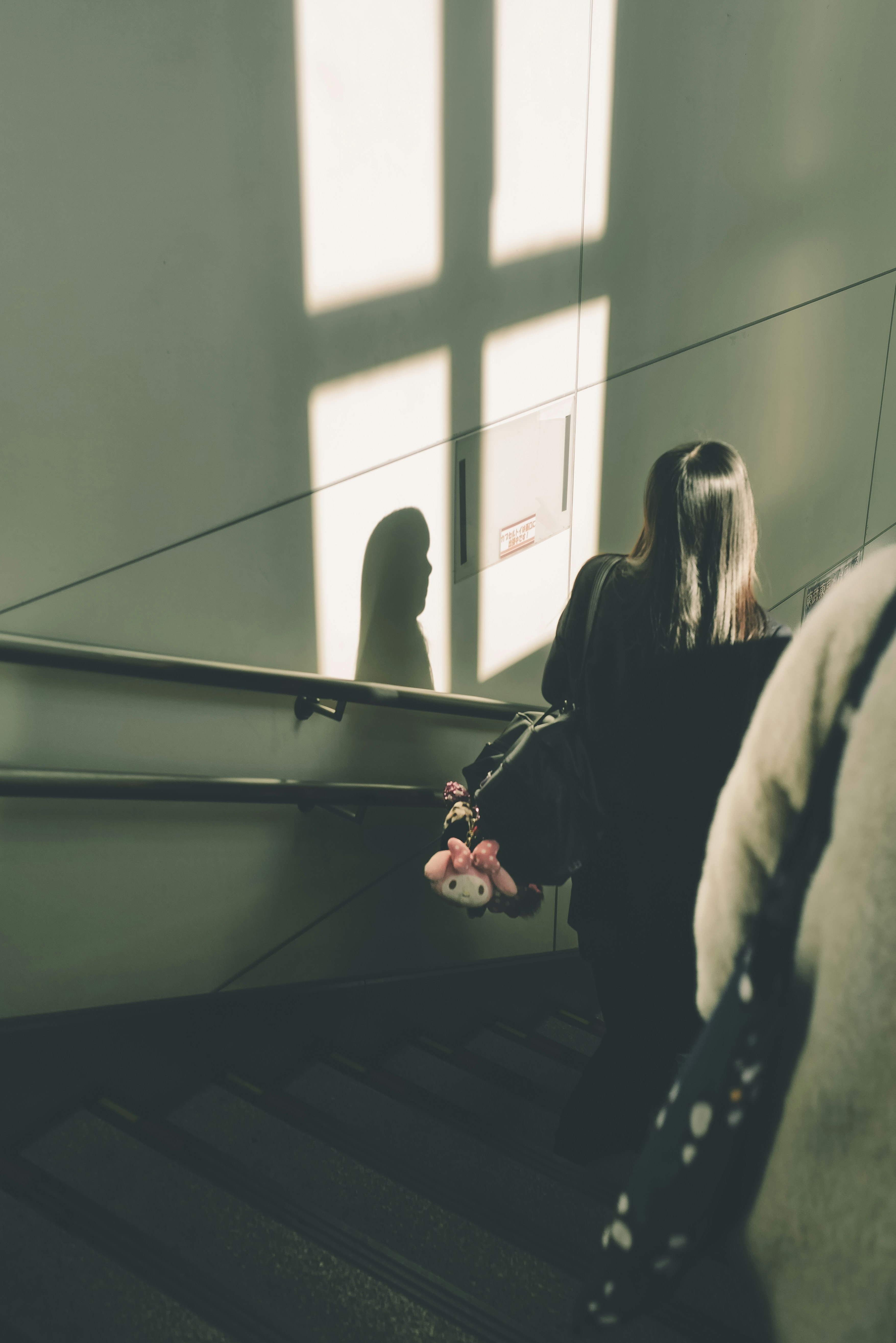 窓の光が差す屋内の階段で会話する人々