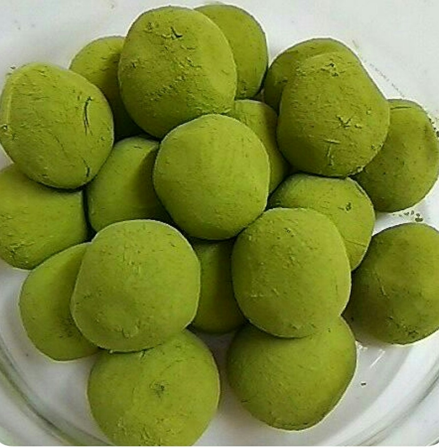 Una colección de dulces verdes redondos dispuestos en un plato de vidrio
