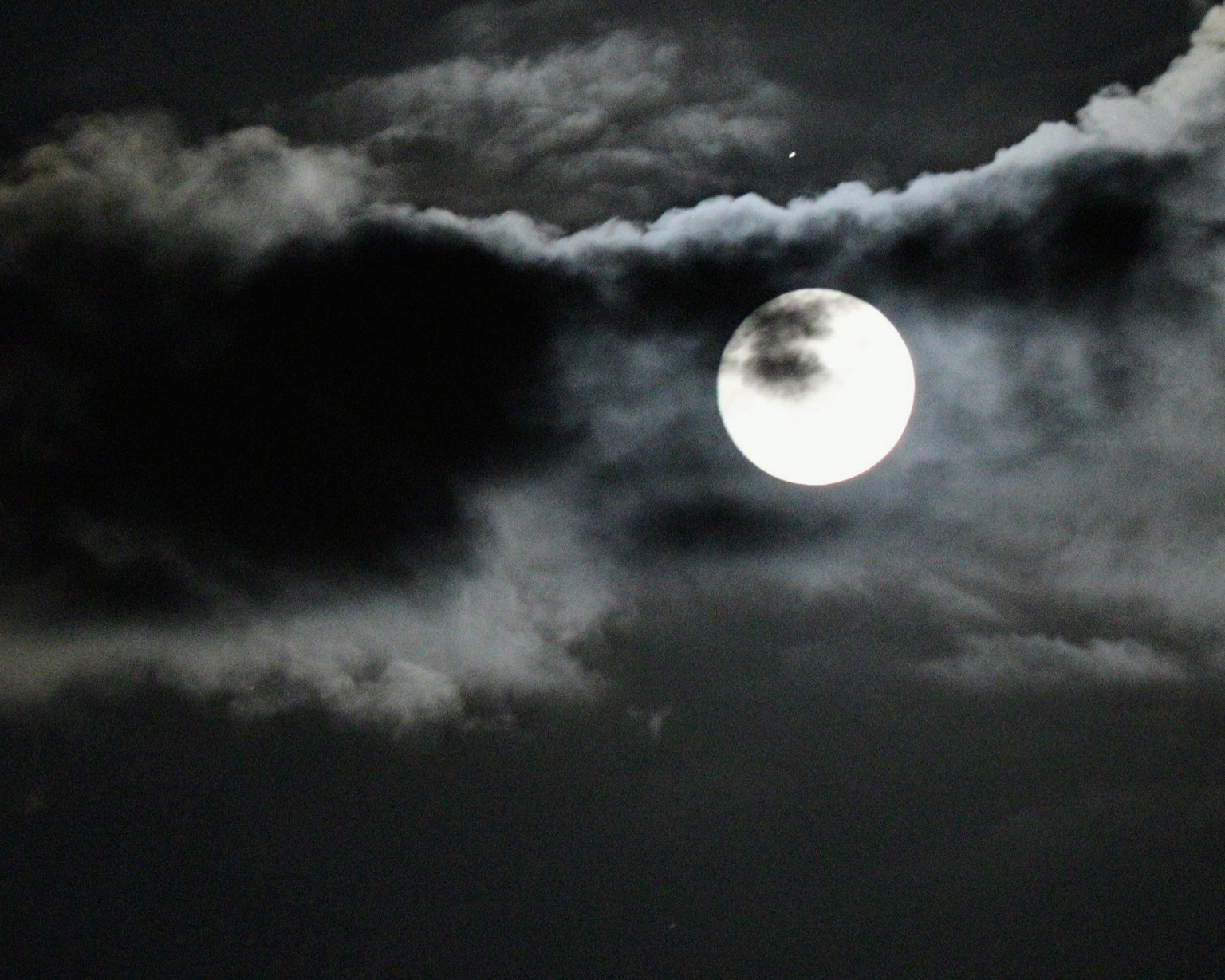 夜空中明亮的滿月與黑暗的雲朵