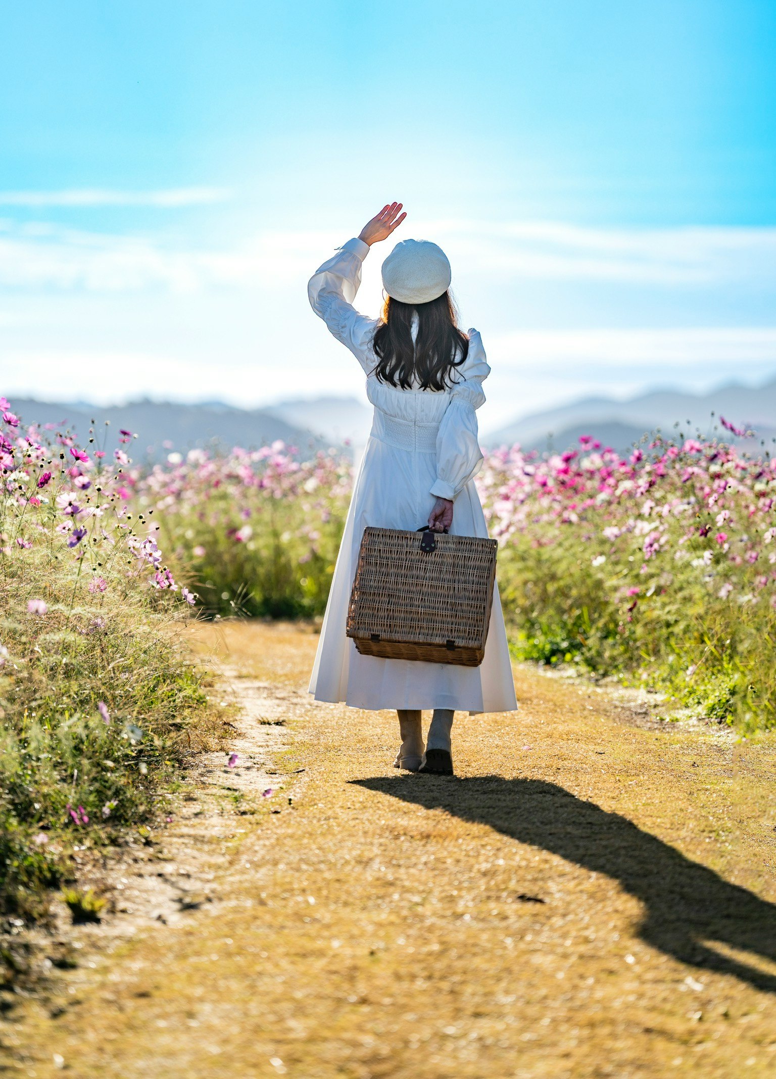 花畑の中を歩く女性が手を振っている