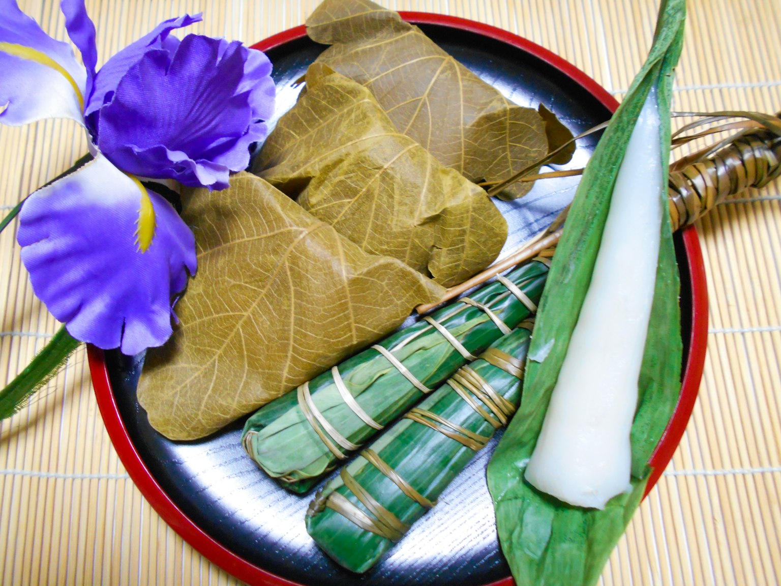 Plato con delicias envueltas en hojas y una flor morada