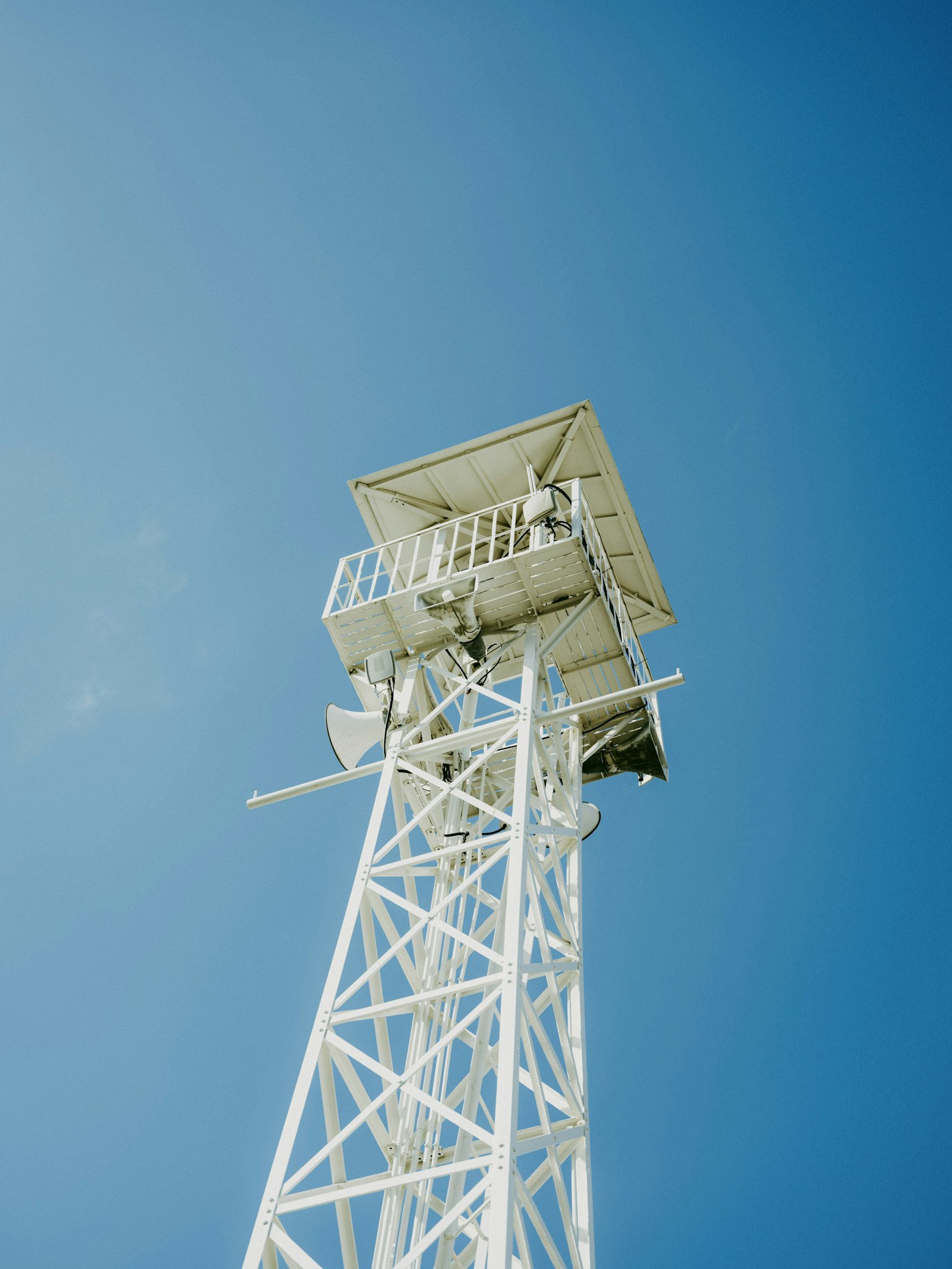 Sebuah menara komunikasi putih menjulang ke langit biru yang cerah