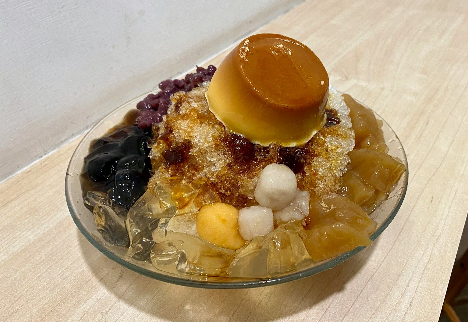 Bol de dessert coloré avec de la glace pilée et des garnitures comme du flan et des perles de tapioca
