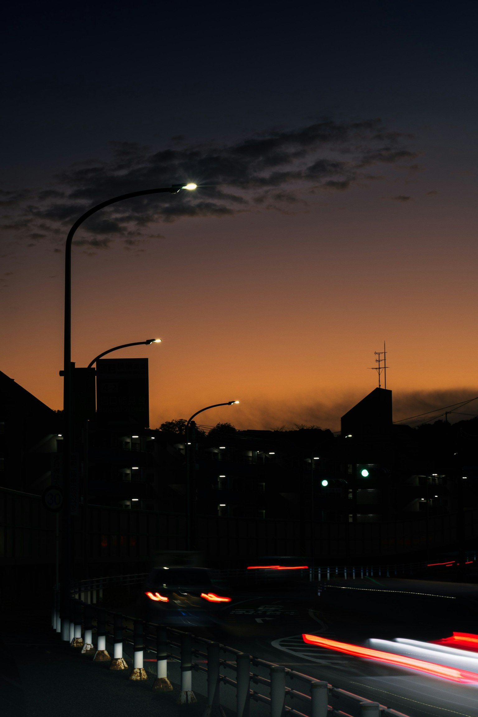Silhouette d'un pont avec des lampadaires sur fond de ville au crépuscule