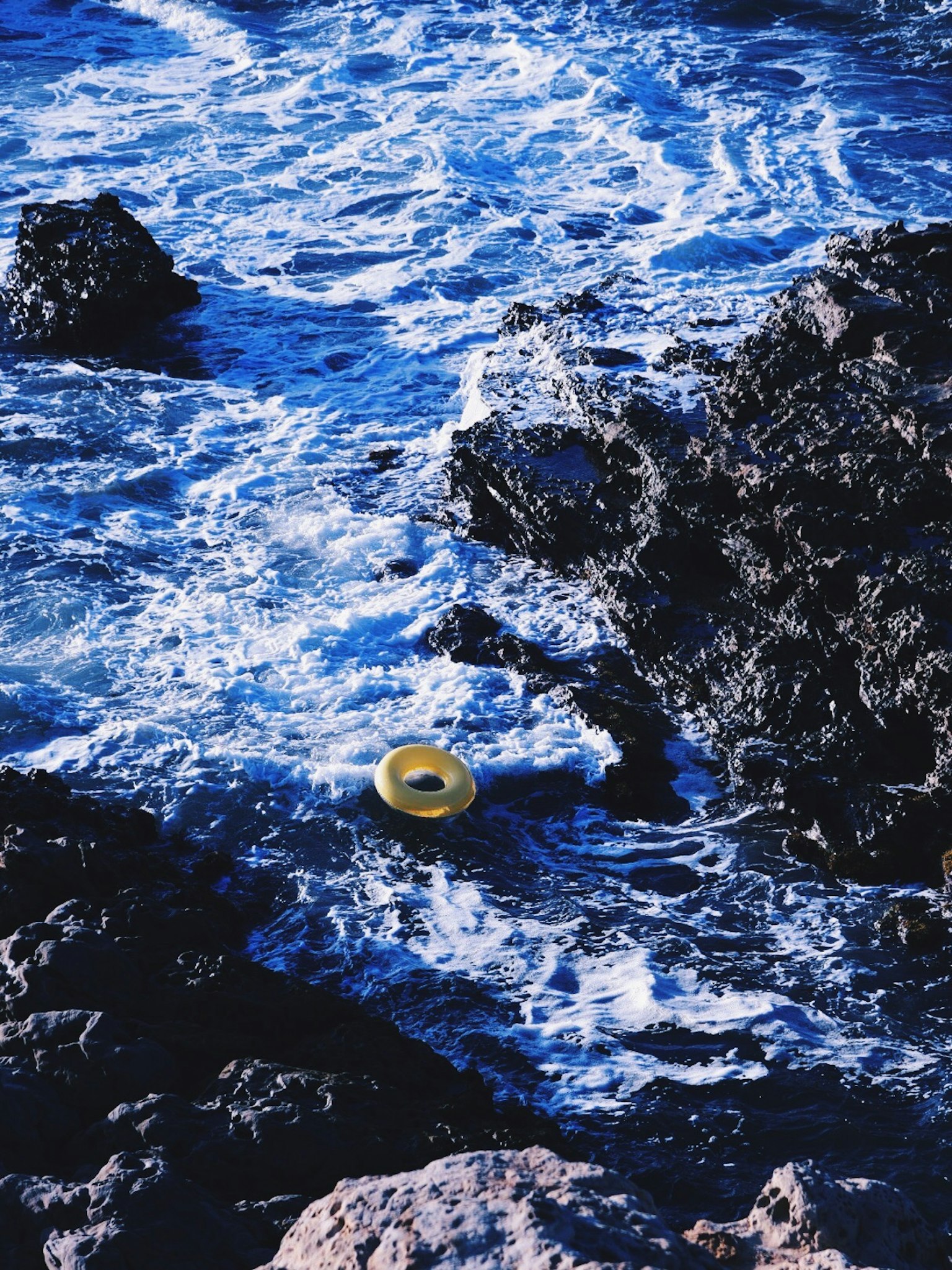 藍色海浪中漂浮的黃色救生圈和岩石