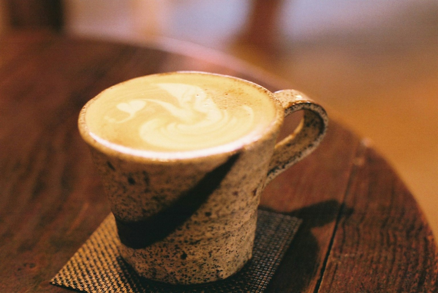 Seni latte krim dalam cangkir keramik