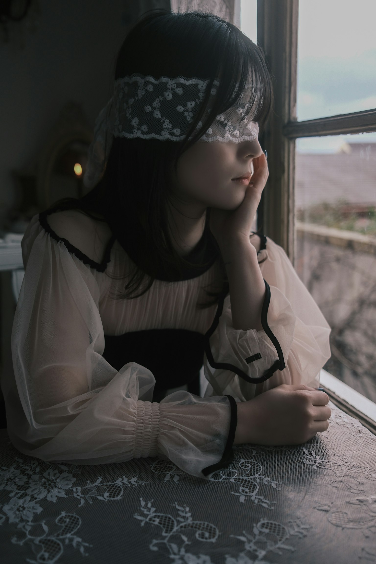 窓辺に座る少女が思索にふける姿 薄い生地のドレスとレースのヘッドバンド