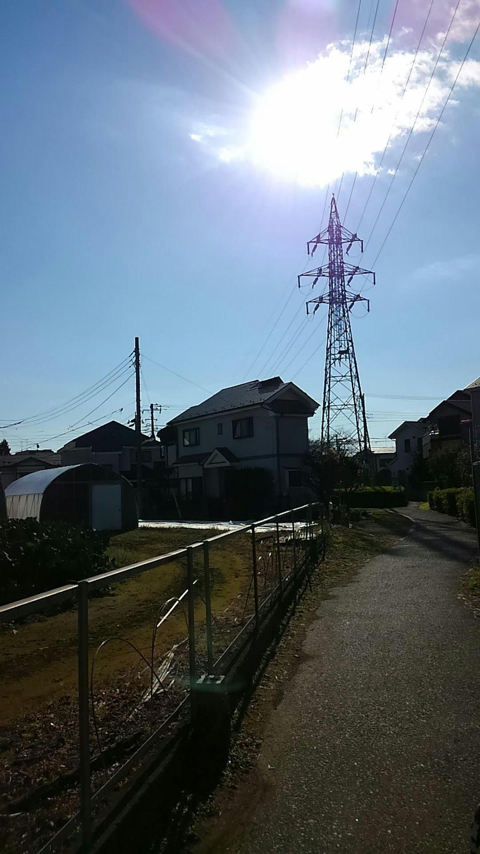 Pemandangan dengan tiang listrik dan rumah di bawah langit biru