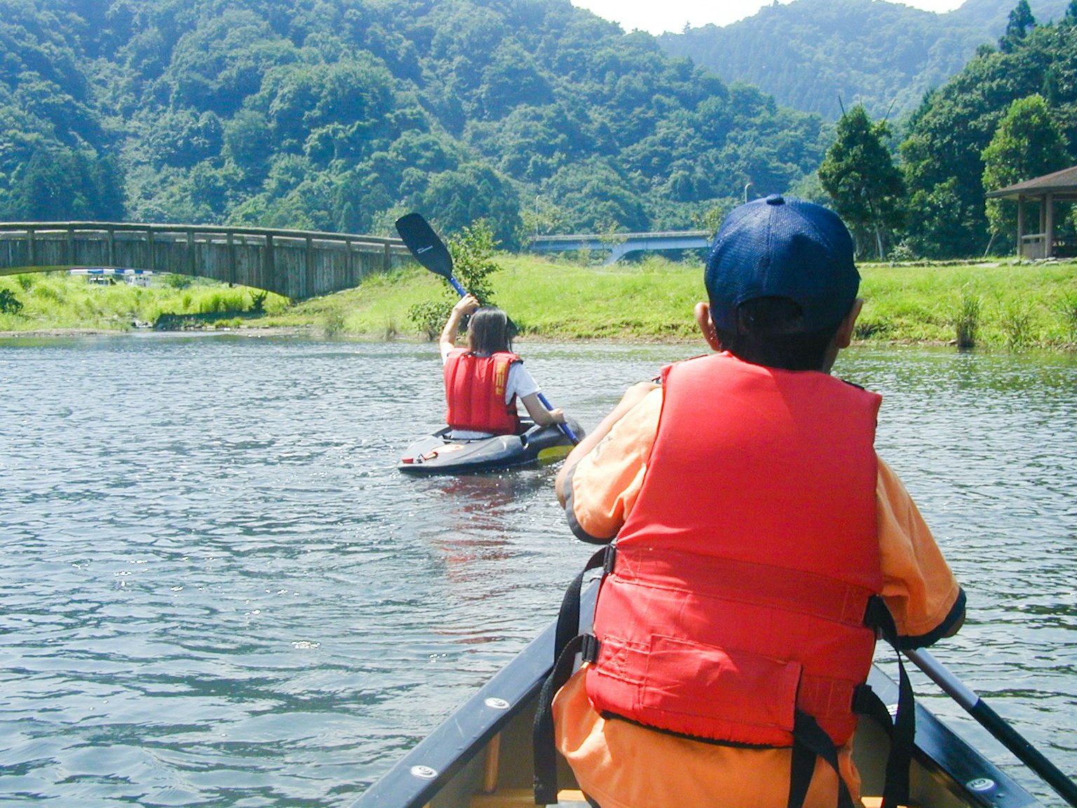 Niños haciendo kayak en un río con montañas verdes de fondo