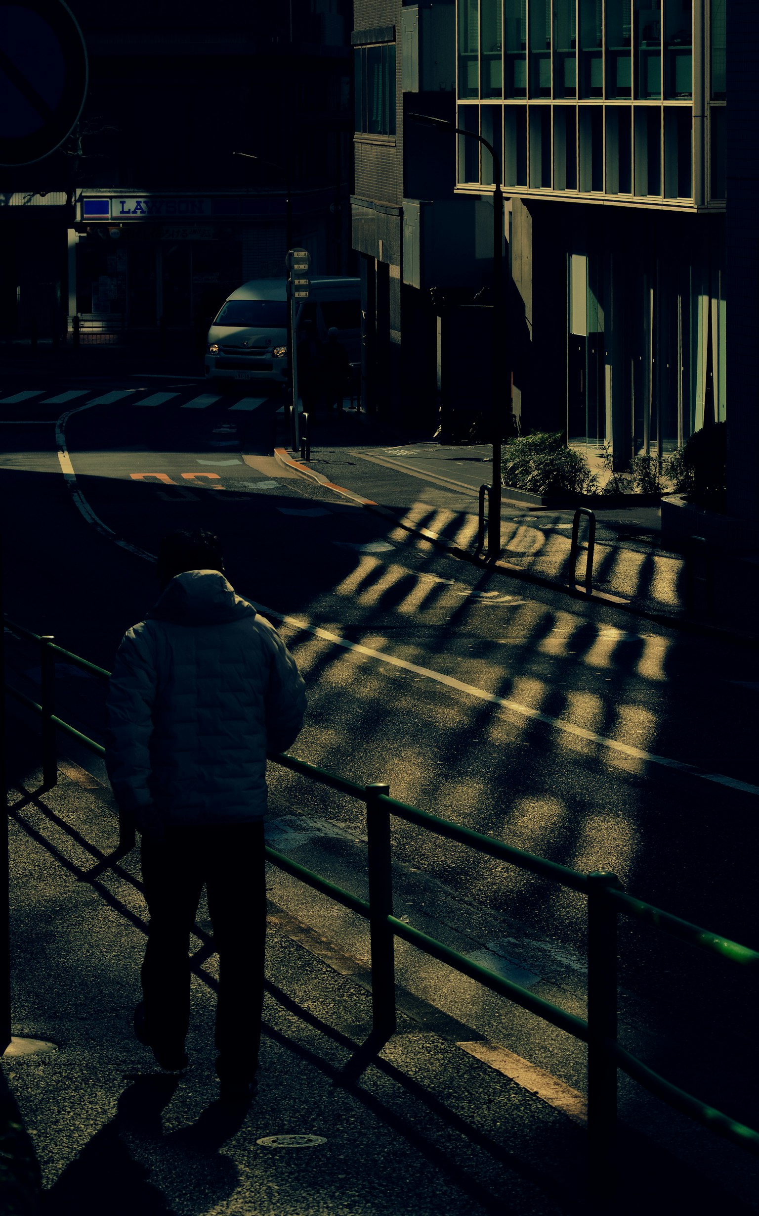 A person walking on a dark street with shadows and urban scenery