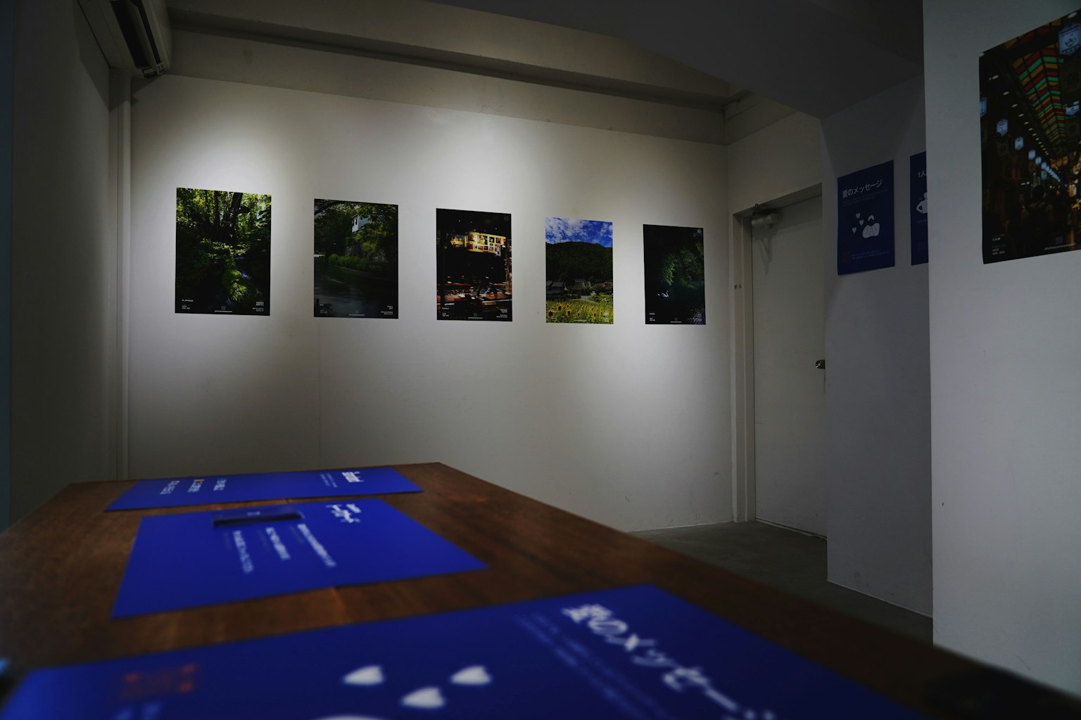 Galerie avec des photographies encadrées sur le mur et une table bleue au premier plan
