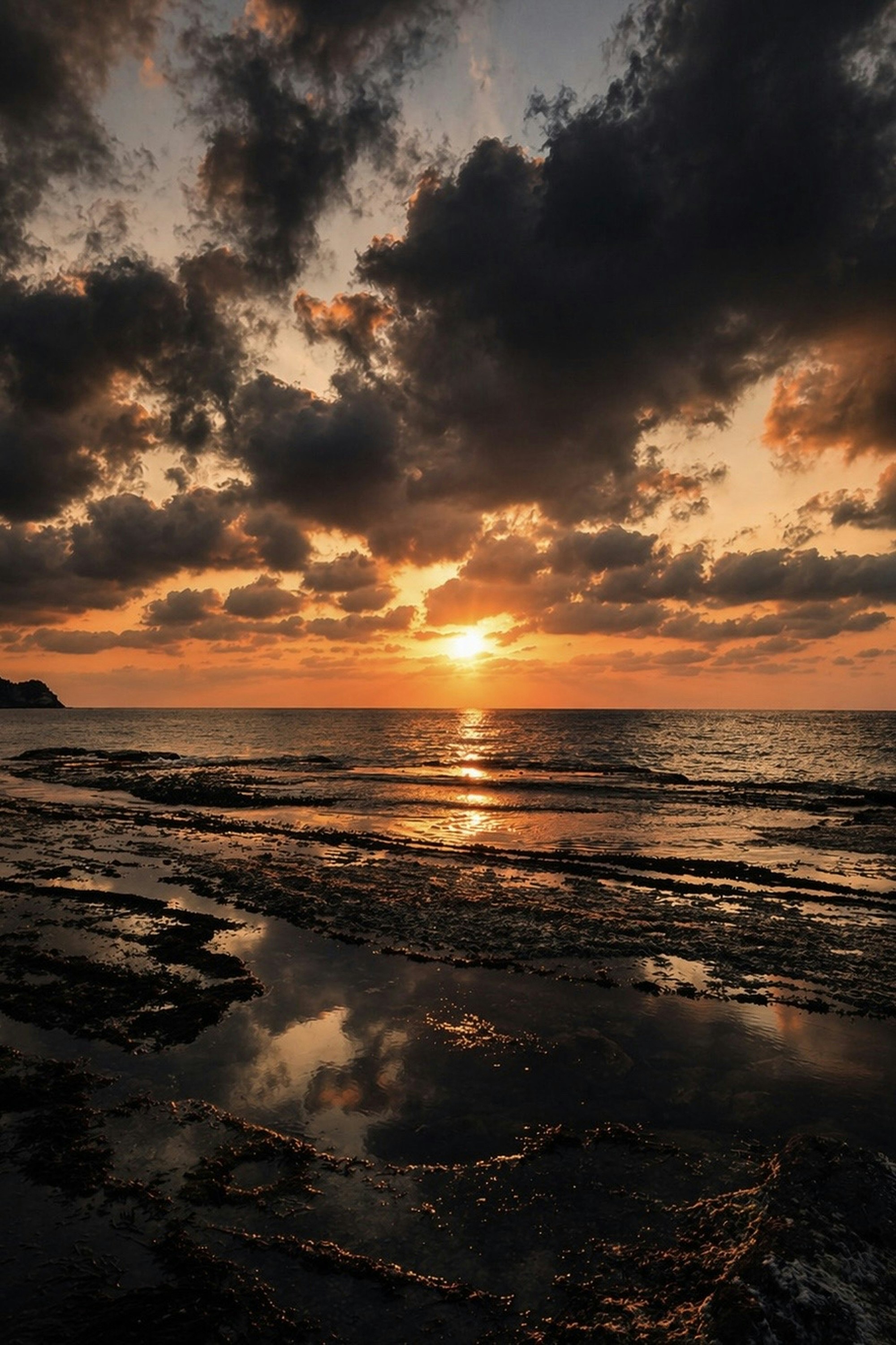 夕日に照らされる海辺の波と雲
