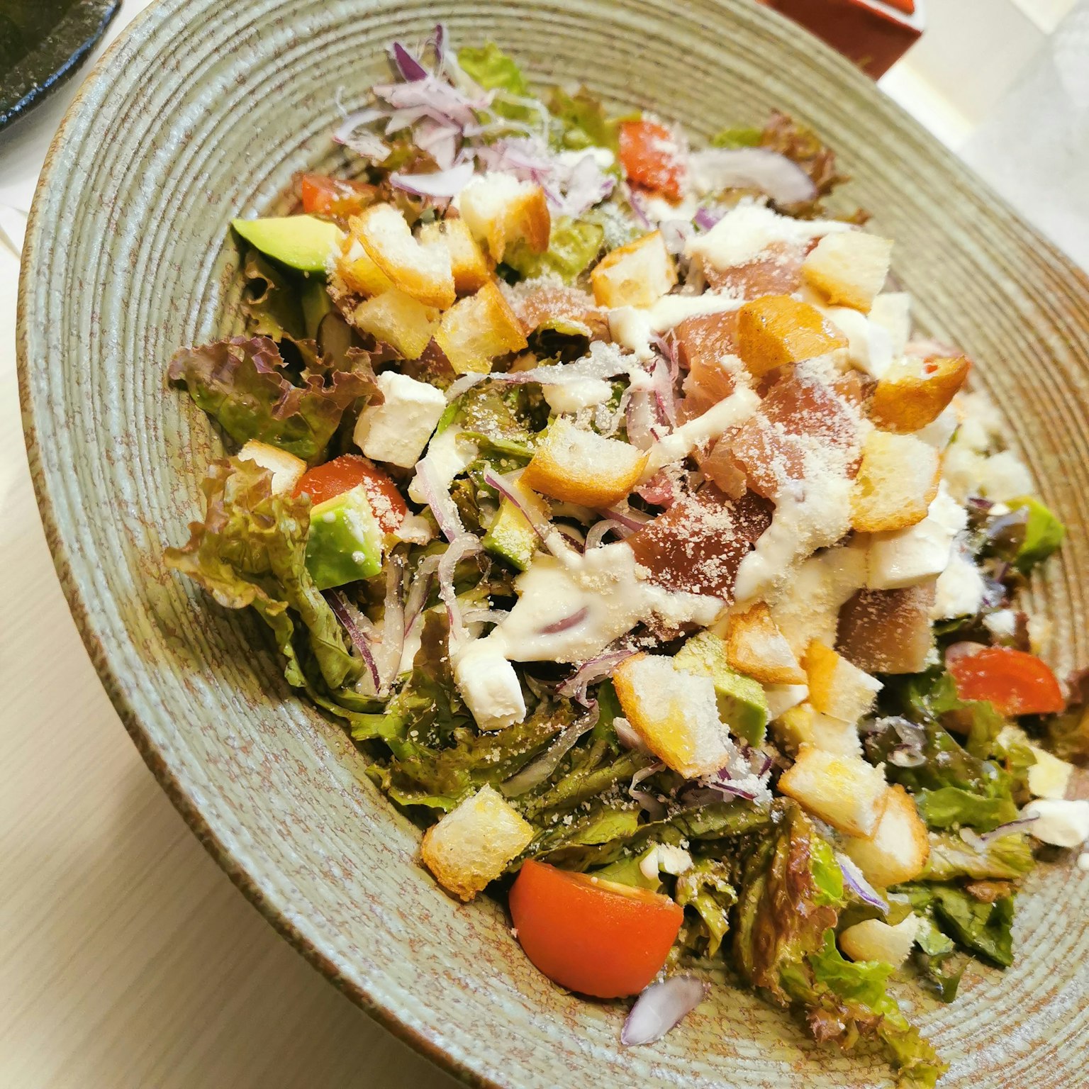 Un'insalata fresca guarnita con pomodori, mele, crostini e formaggio in una ciotola