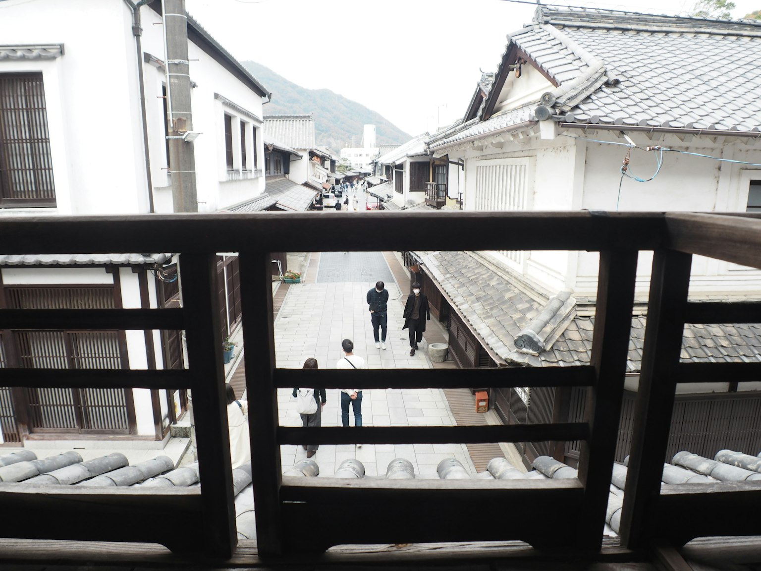 Vista di una strada tranquilla e persone da un balcone in legno