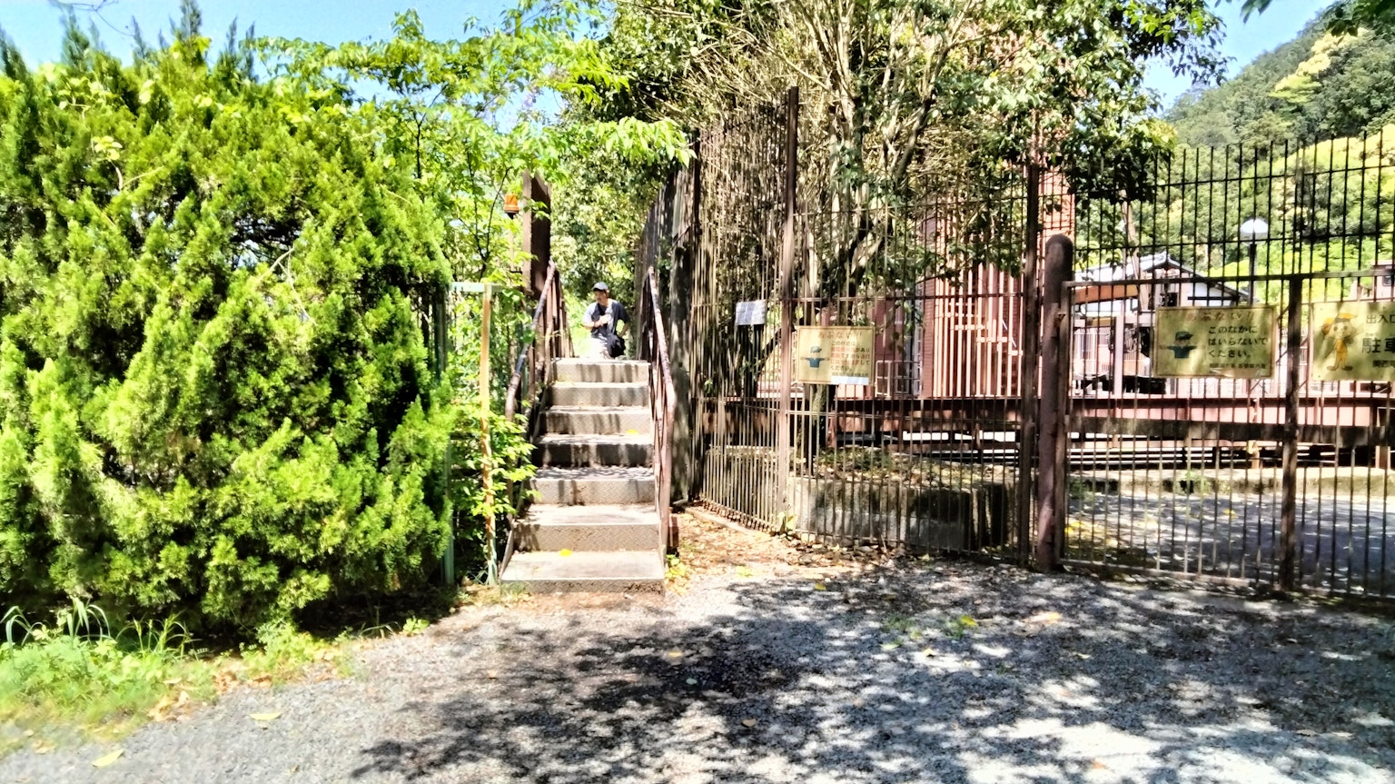 Entrée d'un jardin avec des arbres verts et des escaliers