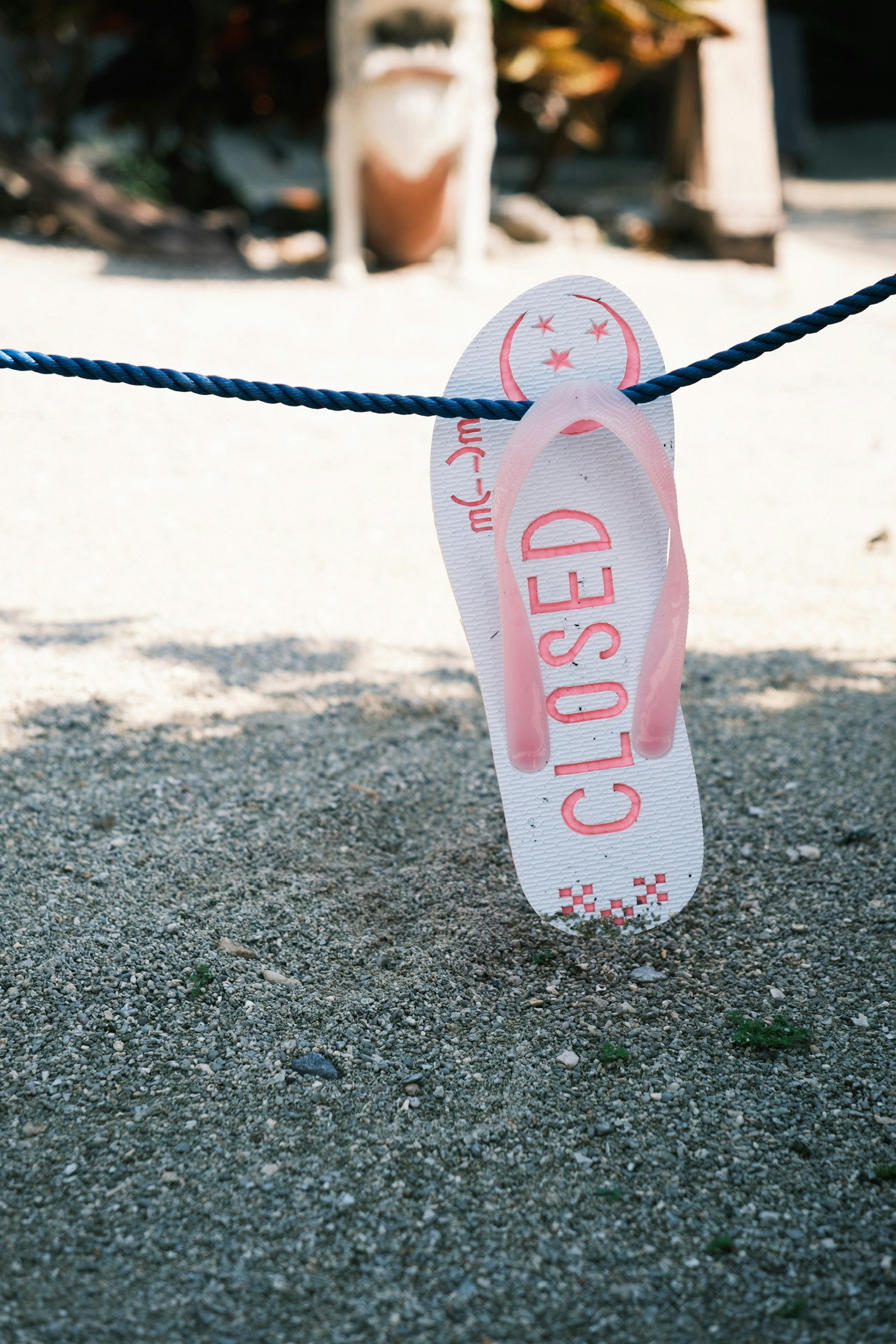 ピンクのビーチサンダルがロープに吊るされている様子で「CLOSED」と書かれている