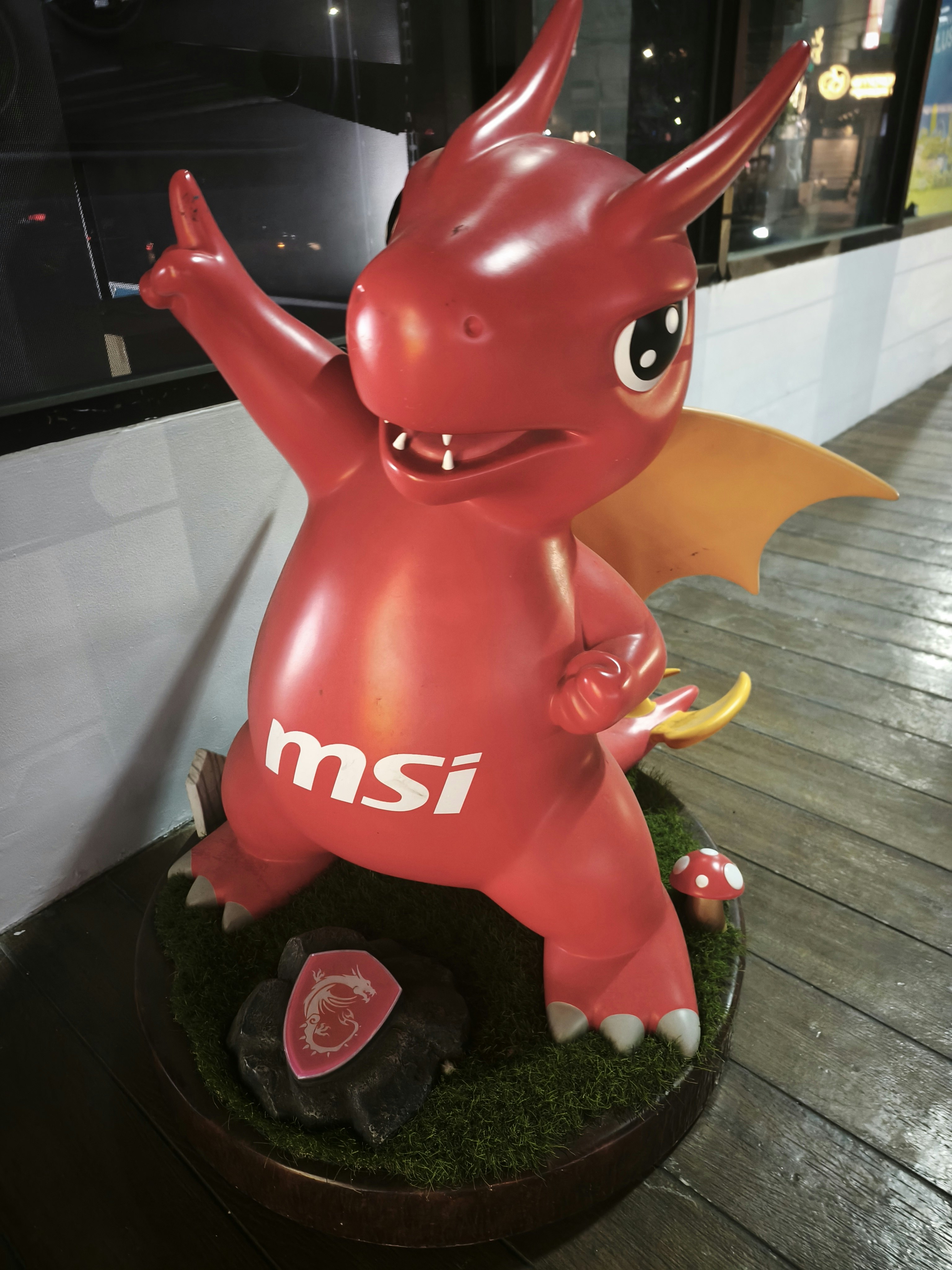 ガラス越しの店内に置かれた赤いキャラクターフィギュア