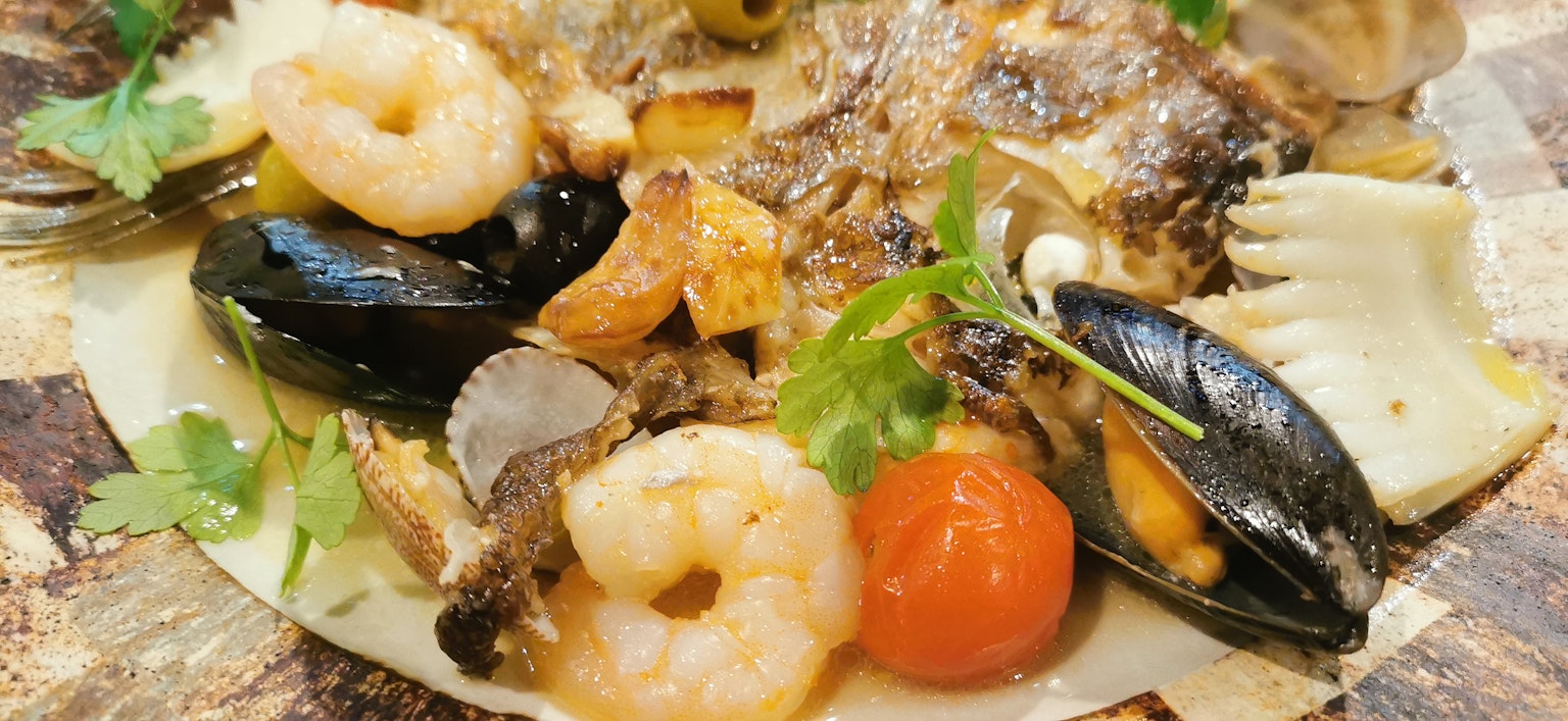 Une assiette de fruits de mer frais comprenant des crevettes, des moules et du poisson garnie d'herbes