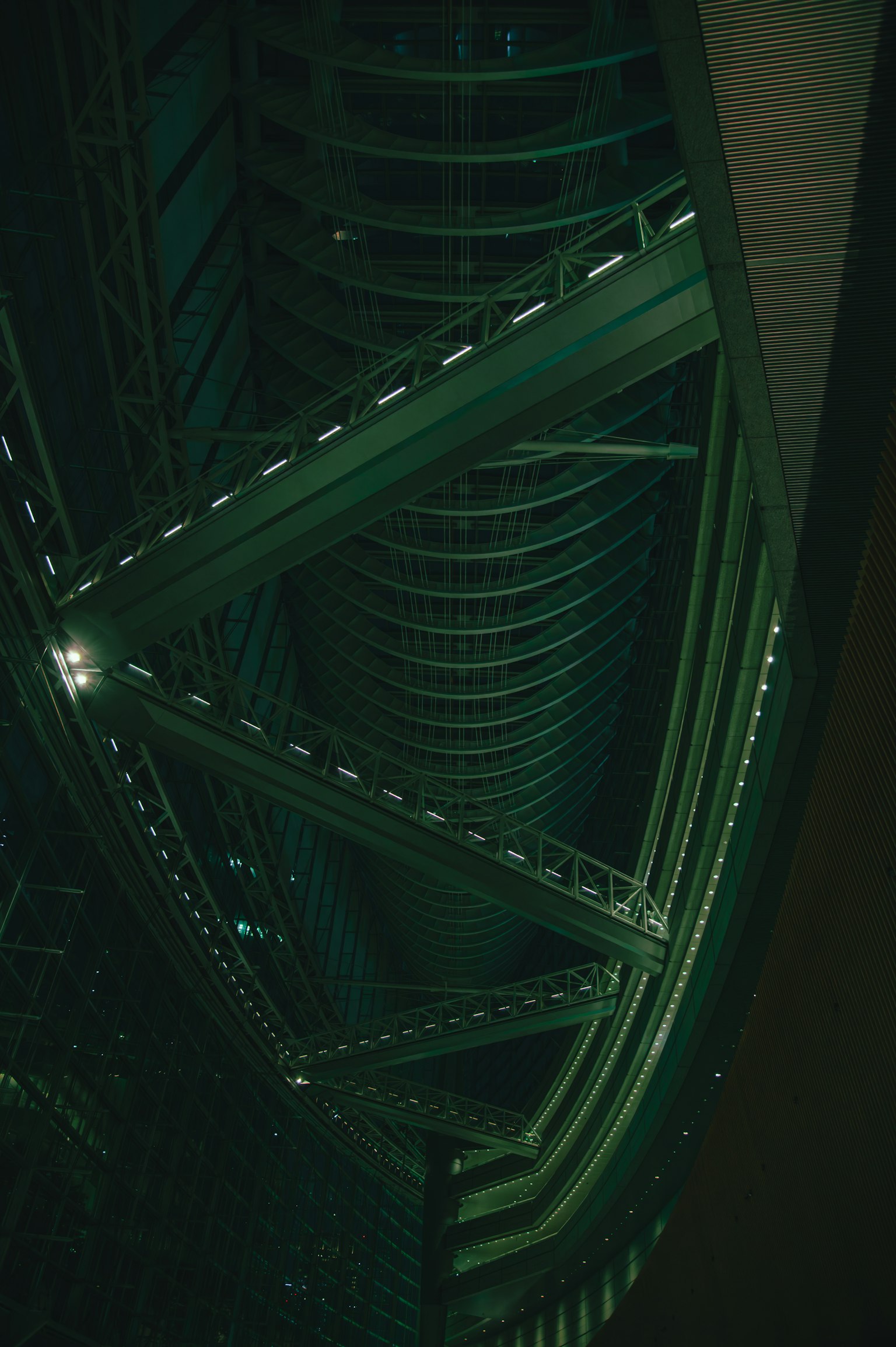 Interior de un edificio con estructuras geométricas y luz verde en un entorno oscuro