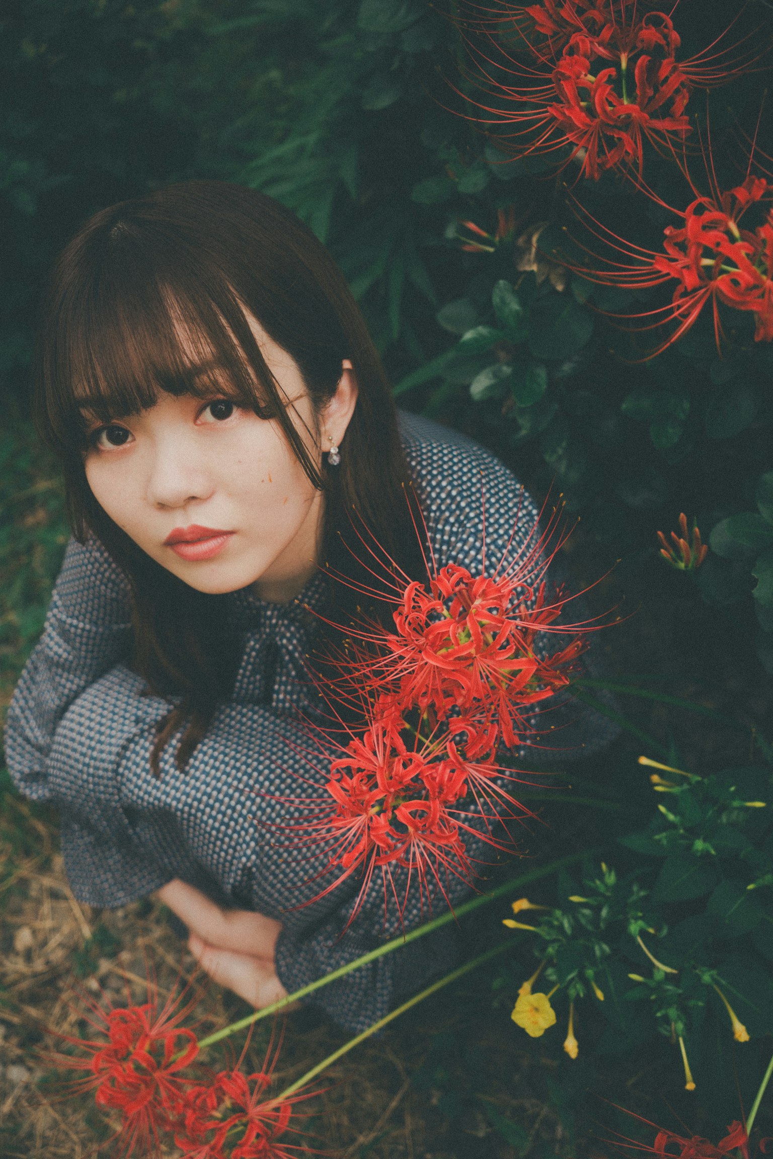 一名女性在鲜艳的红花旁摆姿势
