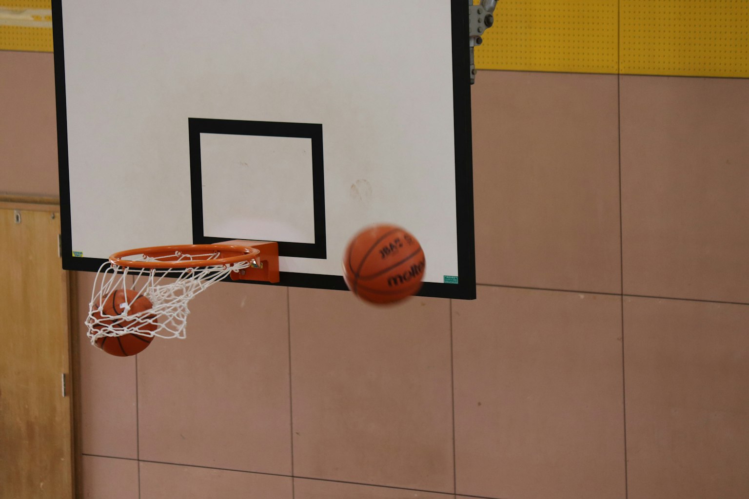Un pallone da basket che si avvicina al canestro in un palazzetto