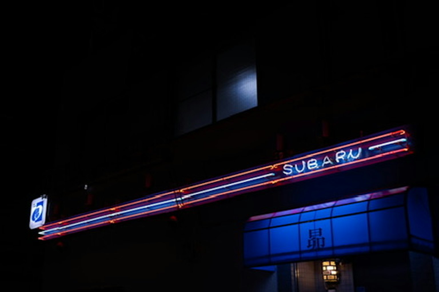 밤에 파란 조명이 비치는 SUBARU 간판