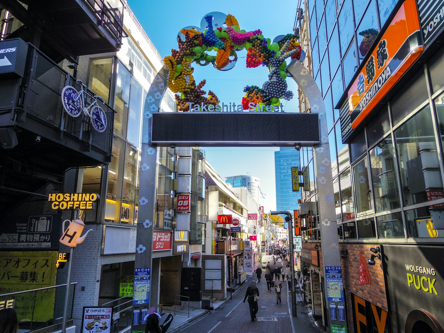 A vibrant street scene featuring a colorful archway with people walking underneath
