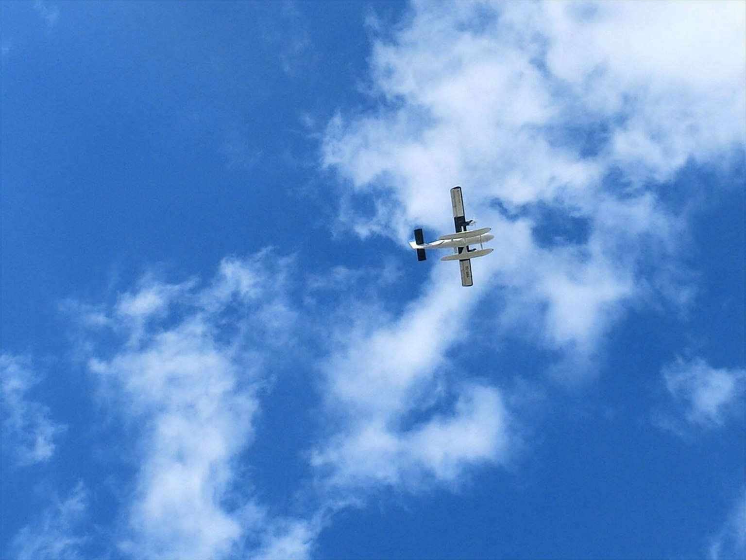 Piccolo aereo che vola in un cielo blu con nuvole bianche