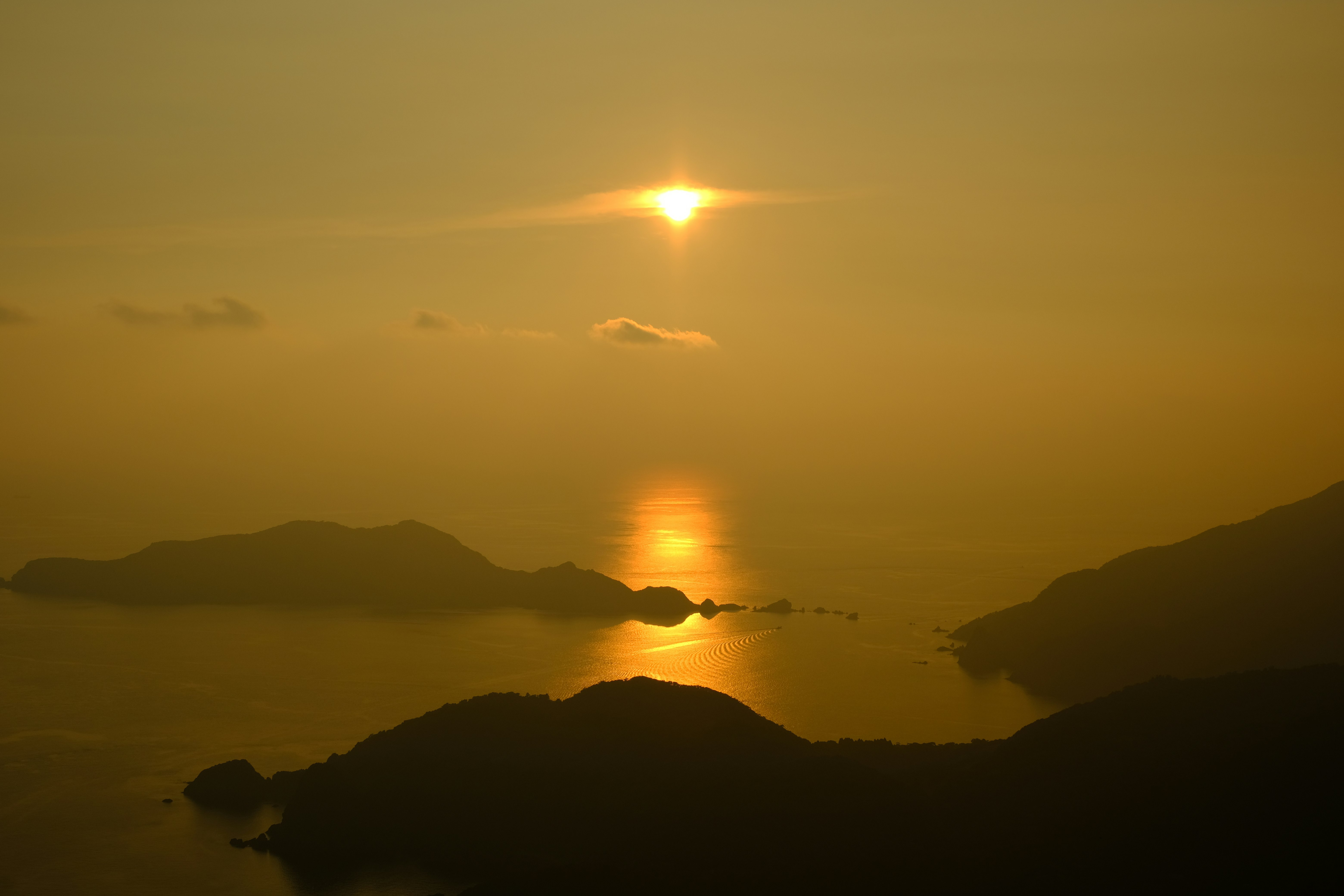 夕日に照らされた入江と島々のシルエットの風景