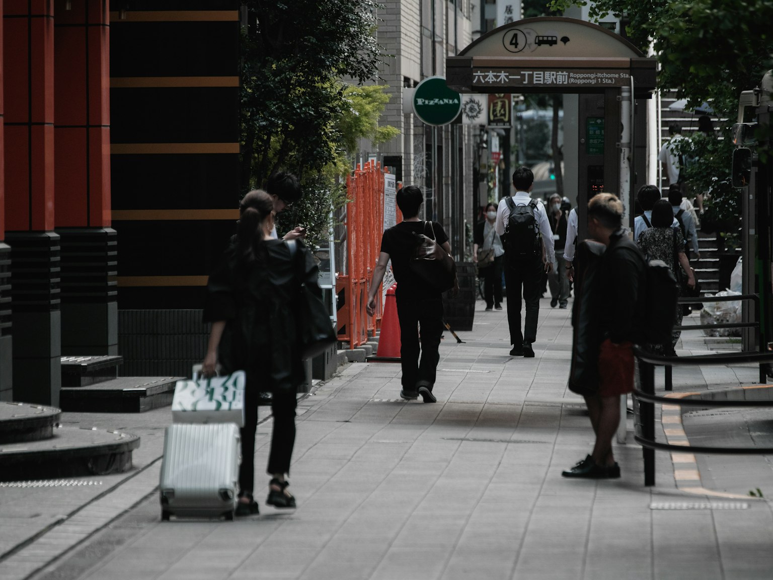 Una strada cittadina con persone che camminano e un viaggiatore con bagagli