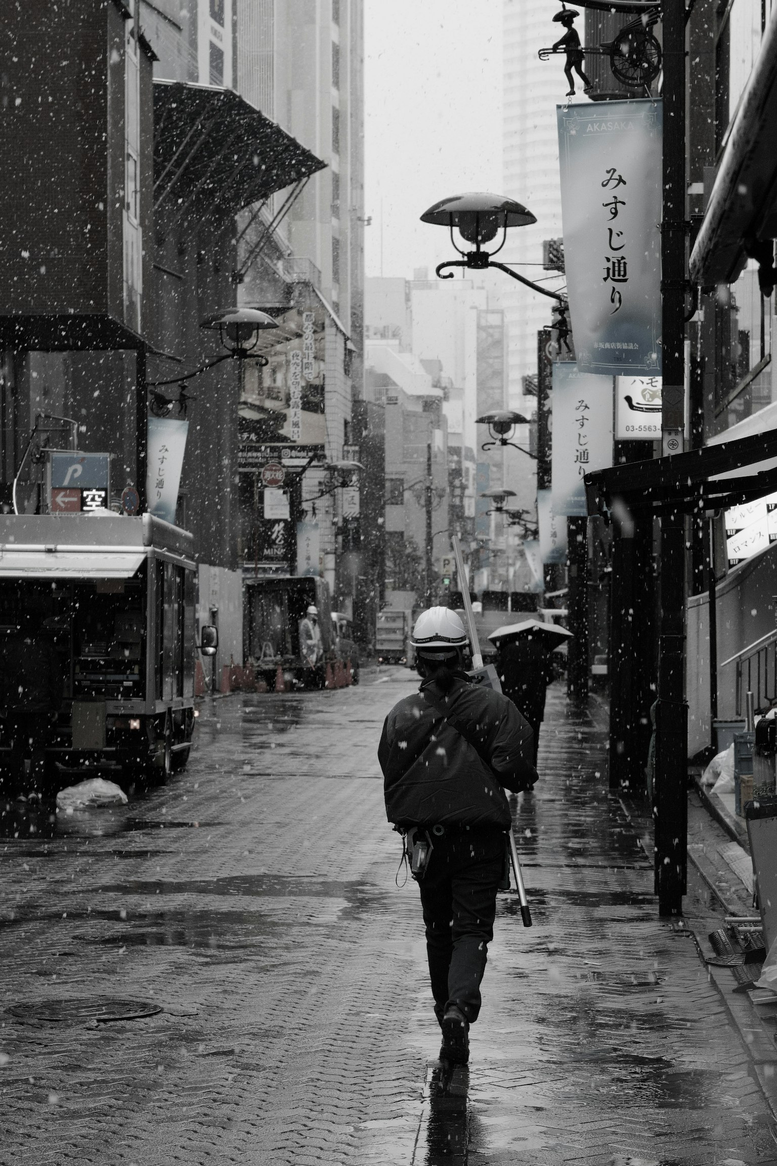A person walking down a snowy street in black and white