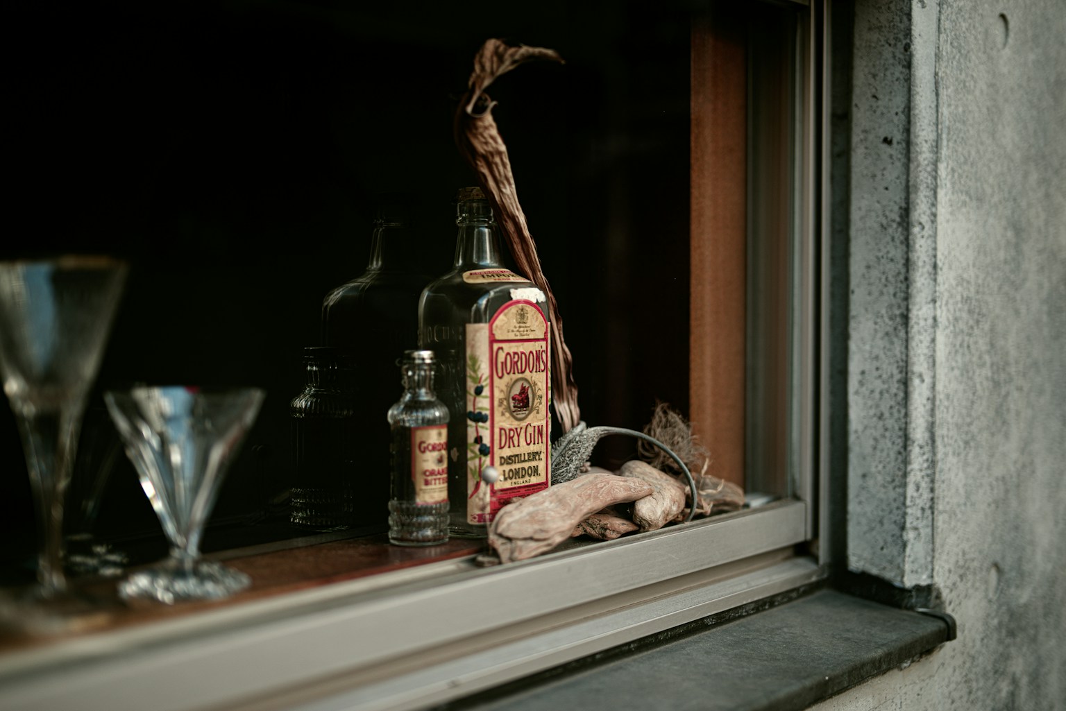 Still life of glassware and bottles on a windowsill with a vintage aesthetic