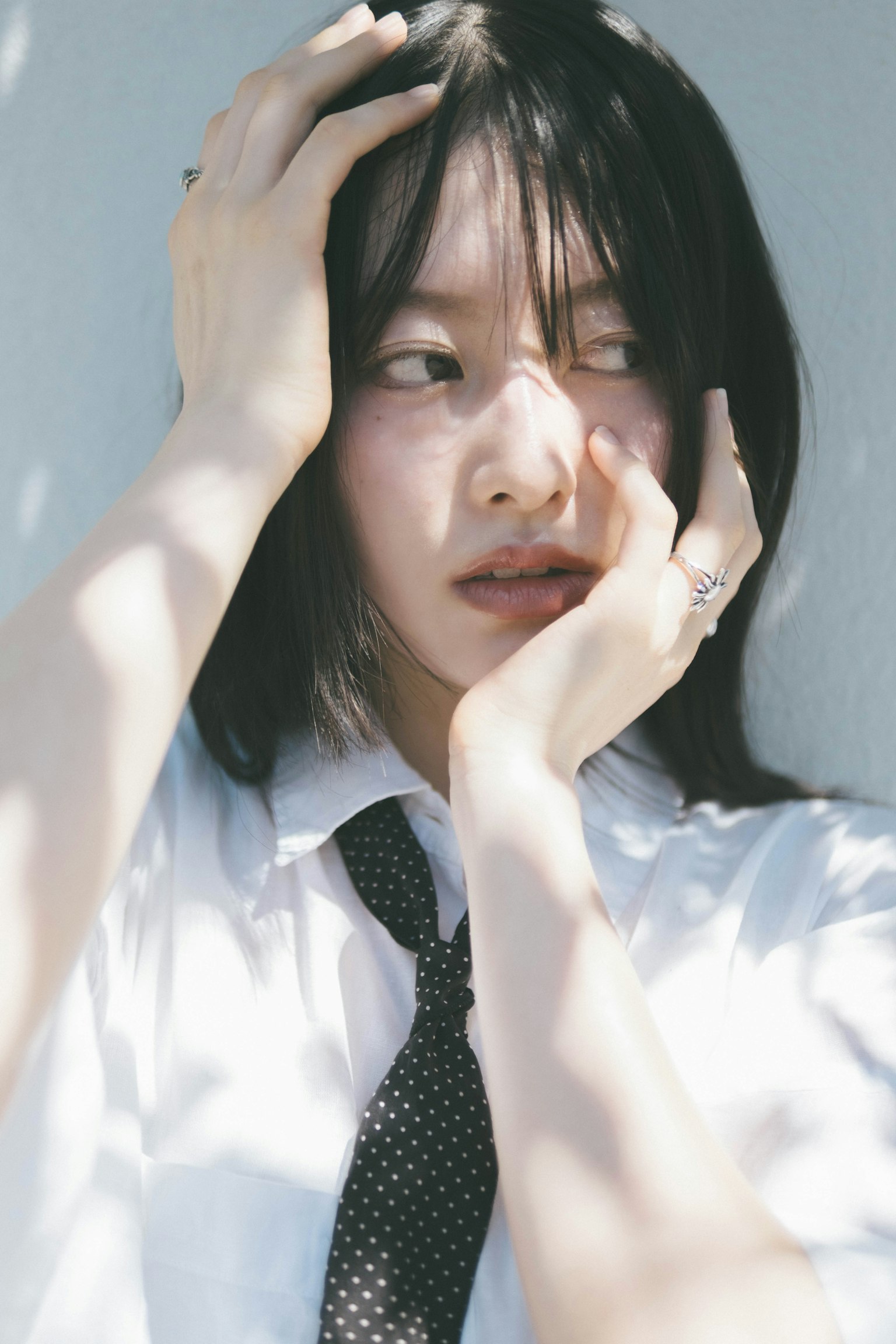 穿着白衬衫和领带的女性手捧着头，神情沉思
