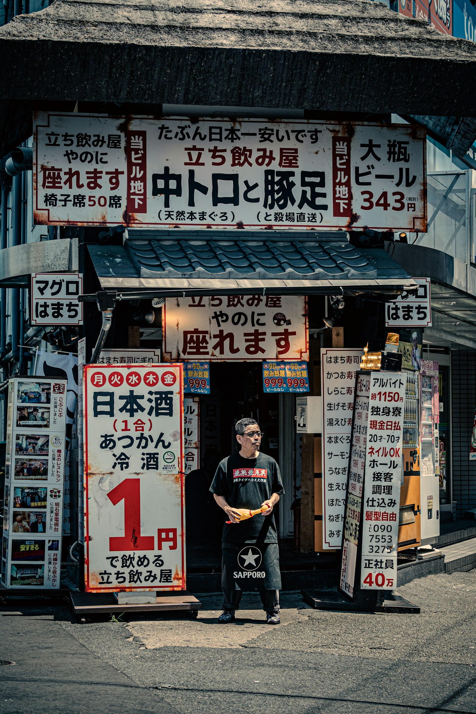 Seorang pria berdiri di depan restoran Jepang dengan berbagai papan dan menu