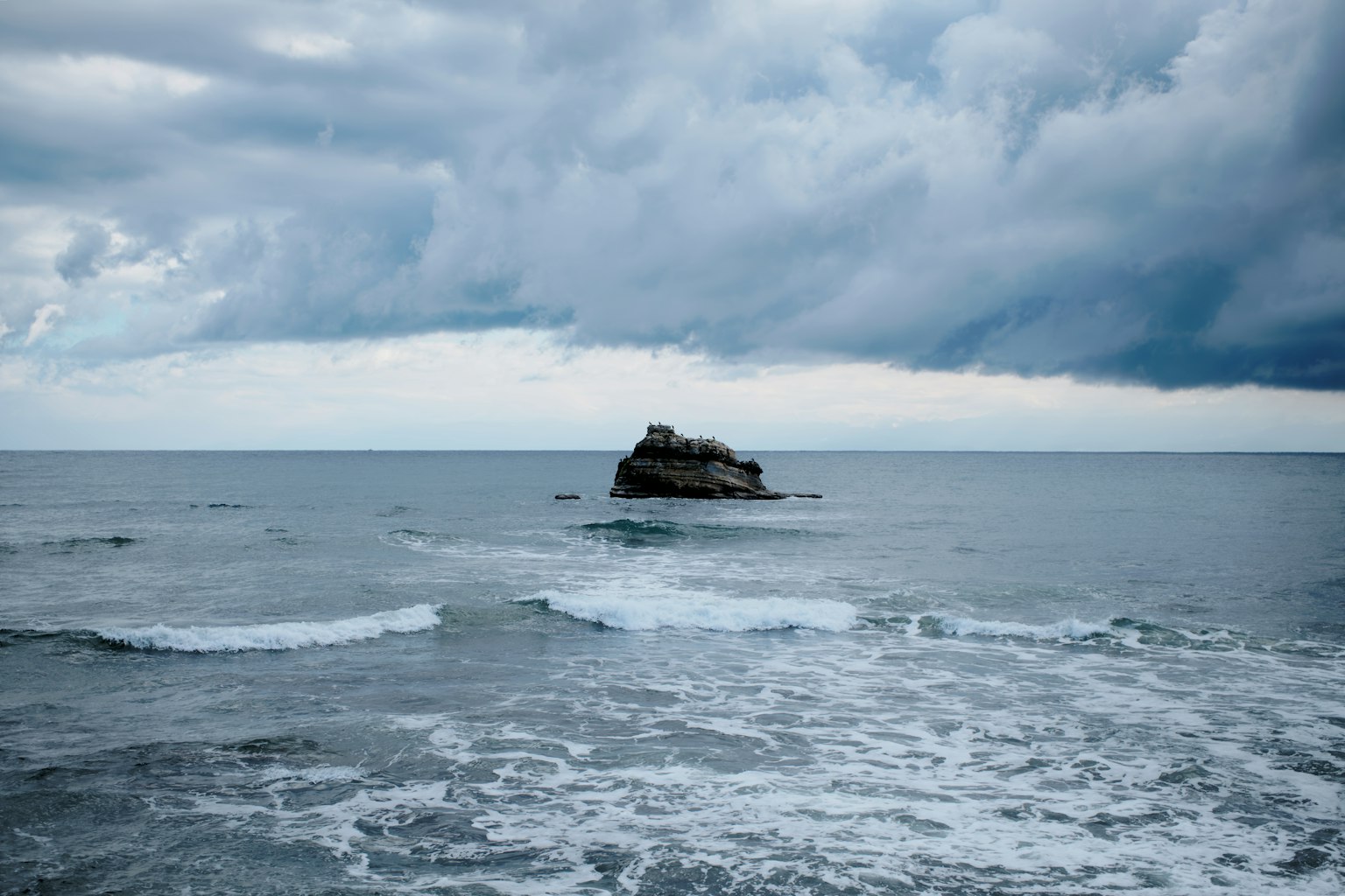 Una piccola isola rocciosa nell'oceano sotto un cielo nuvoloso