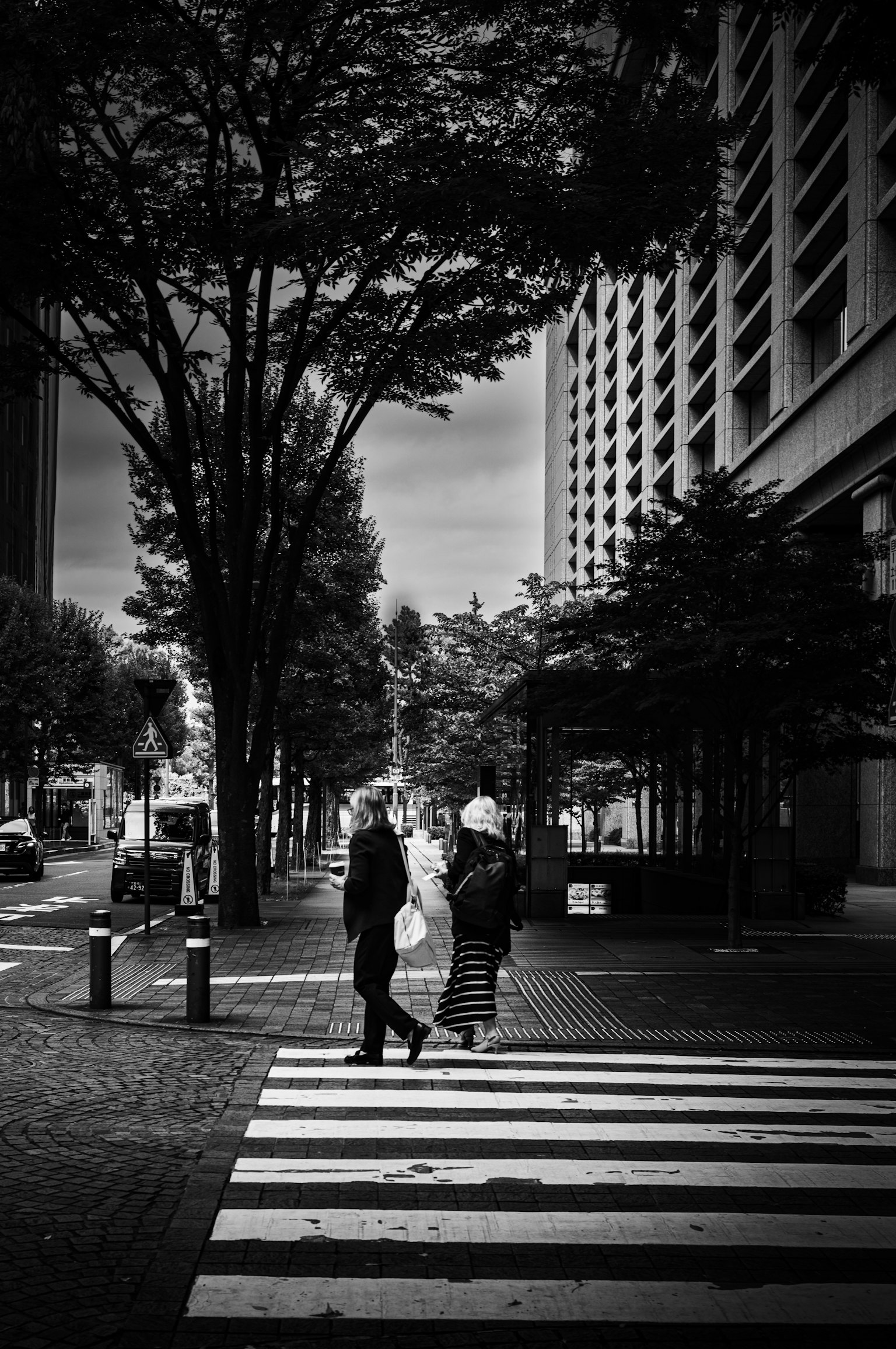 Silhouette di un uomo e una donna che attraversano un attraversamento pedonale in un paesaggio urbano in bianco e nero