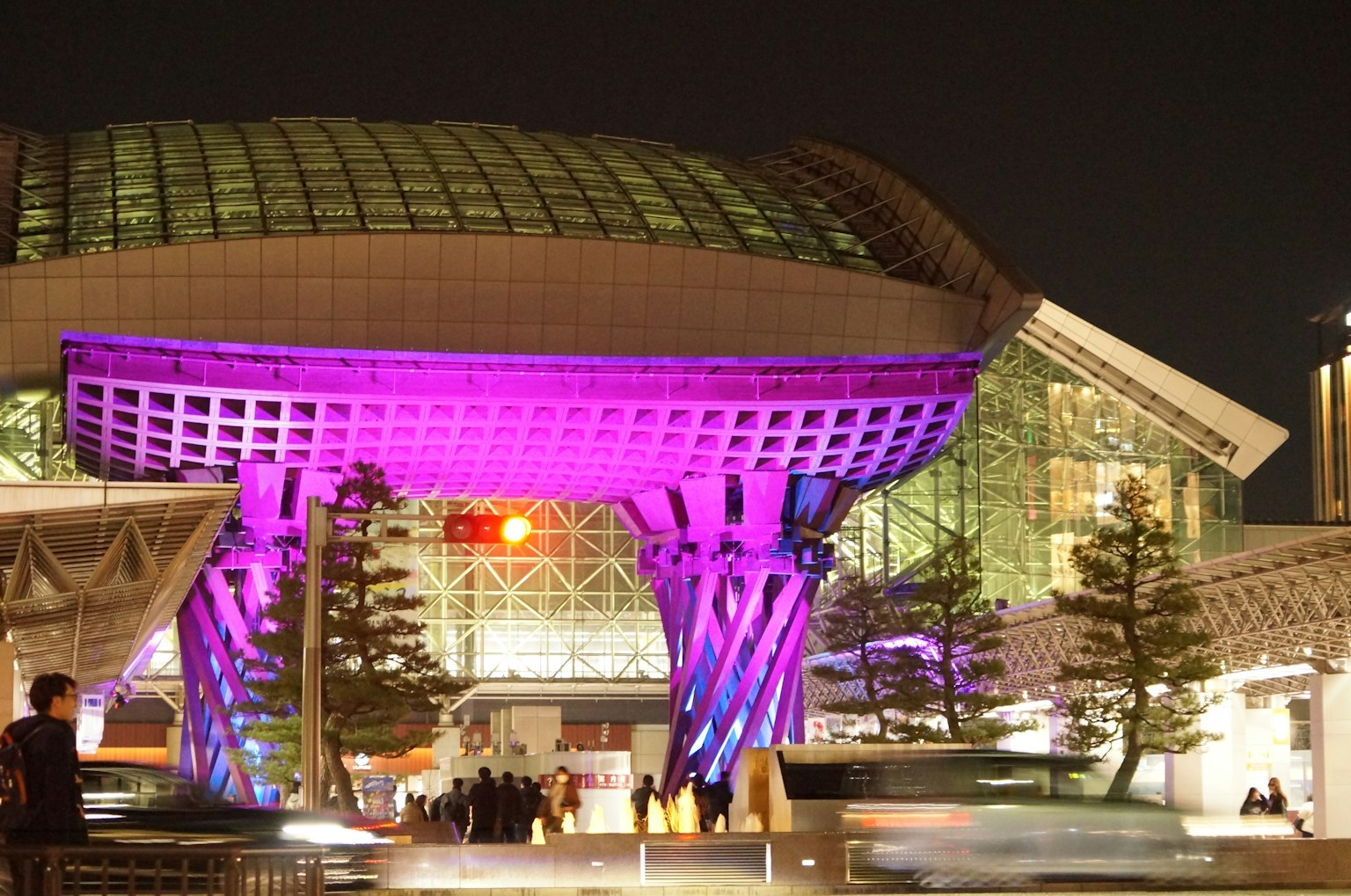 Large structure with purple lighting at a train station at night