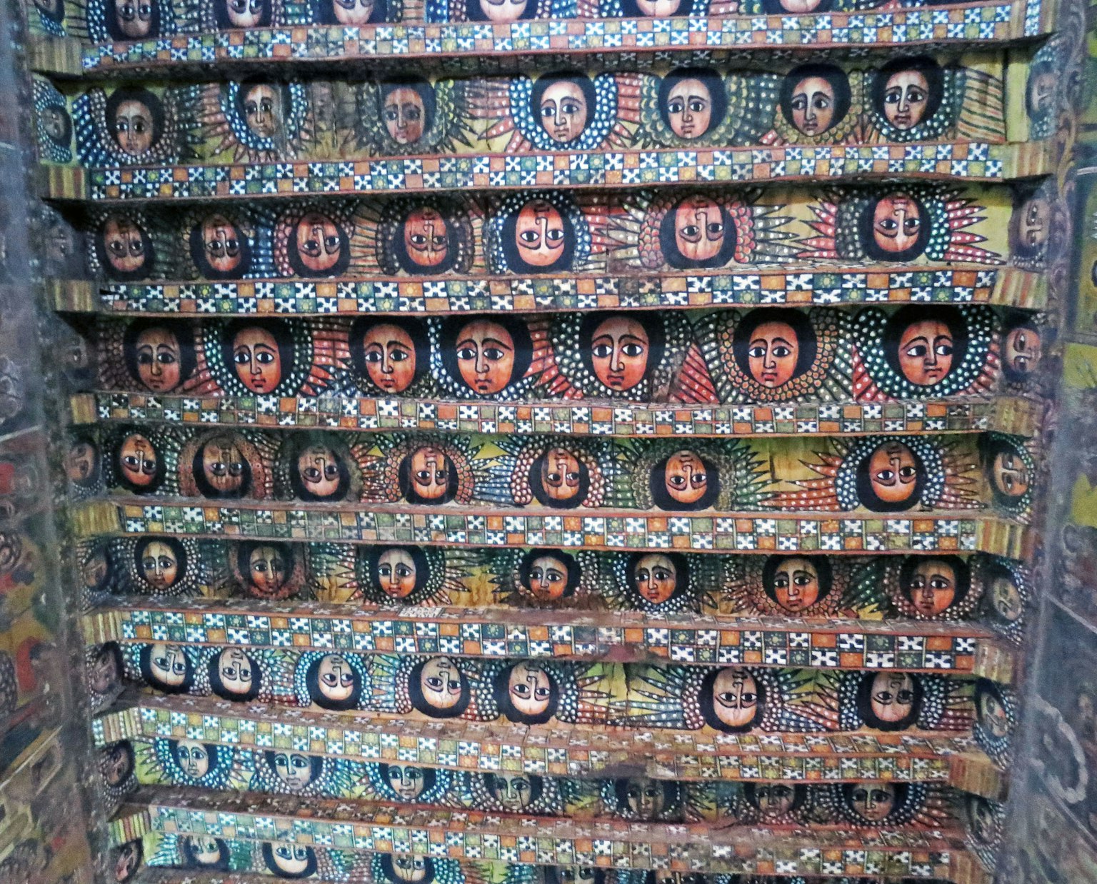 Estanterías de madera coloridas adornadas con diversos rostros pintados