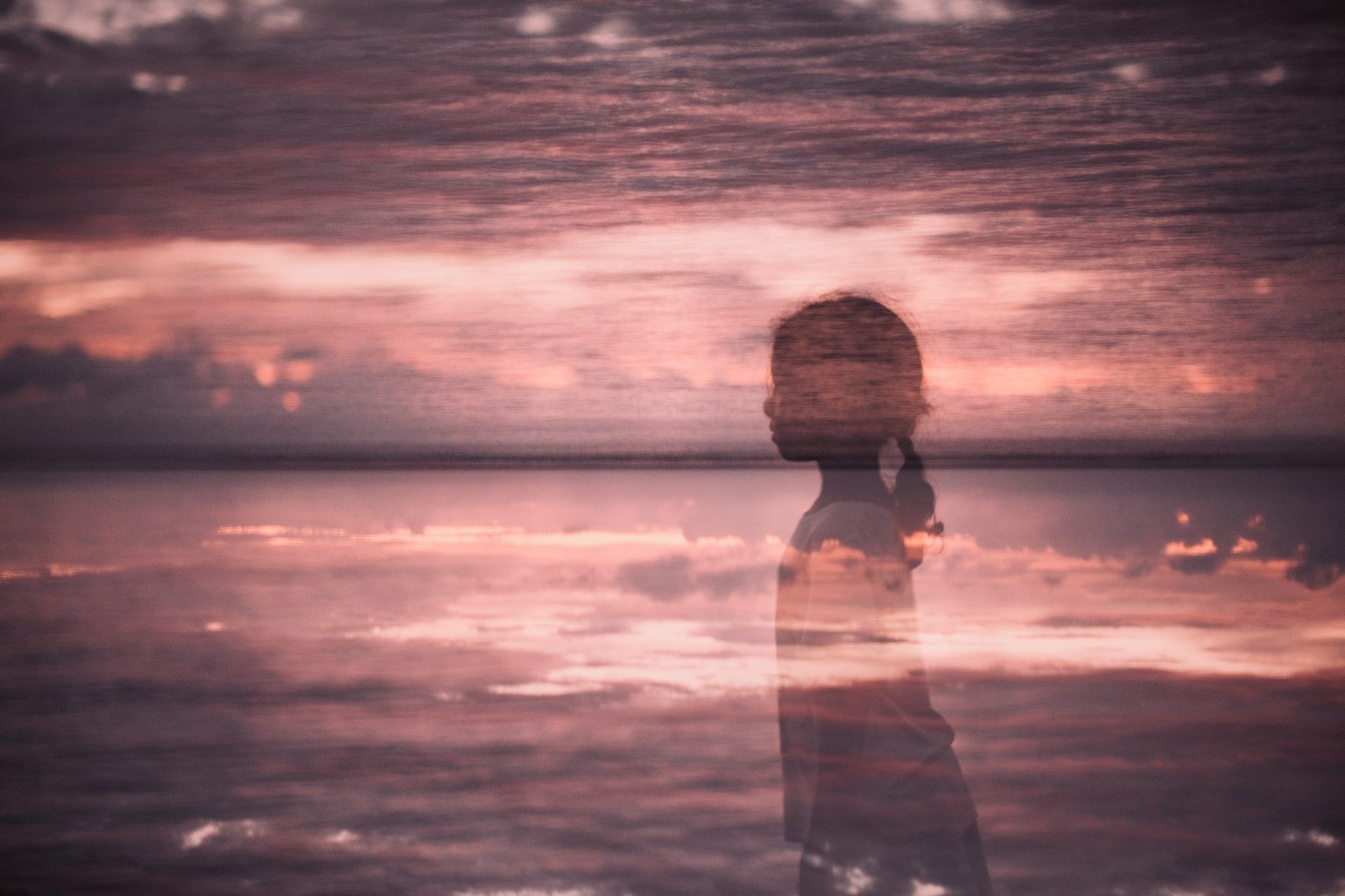 Silhouette di una ragazza riflessa sull'acqua con un bellissimo tramonto