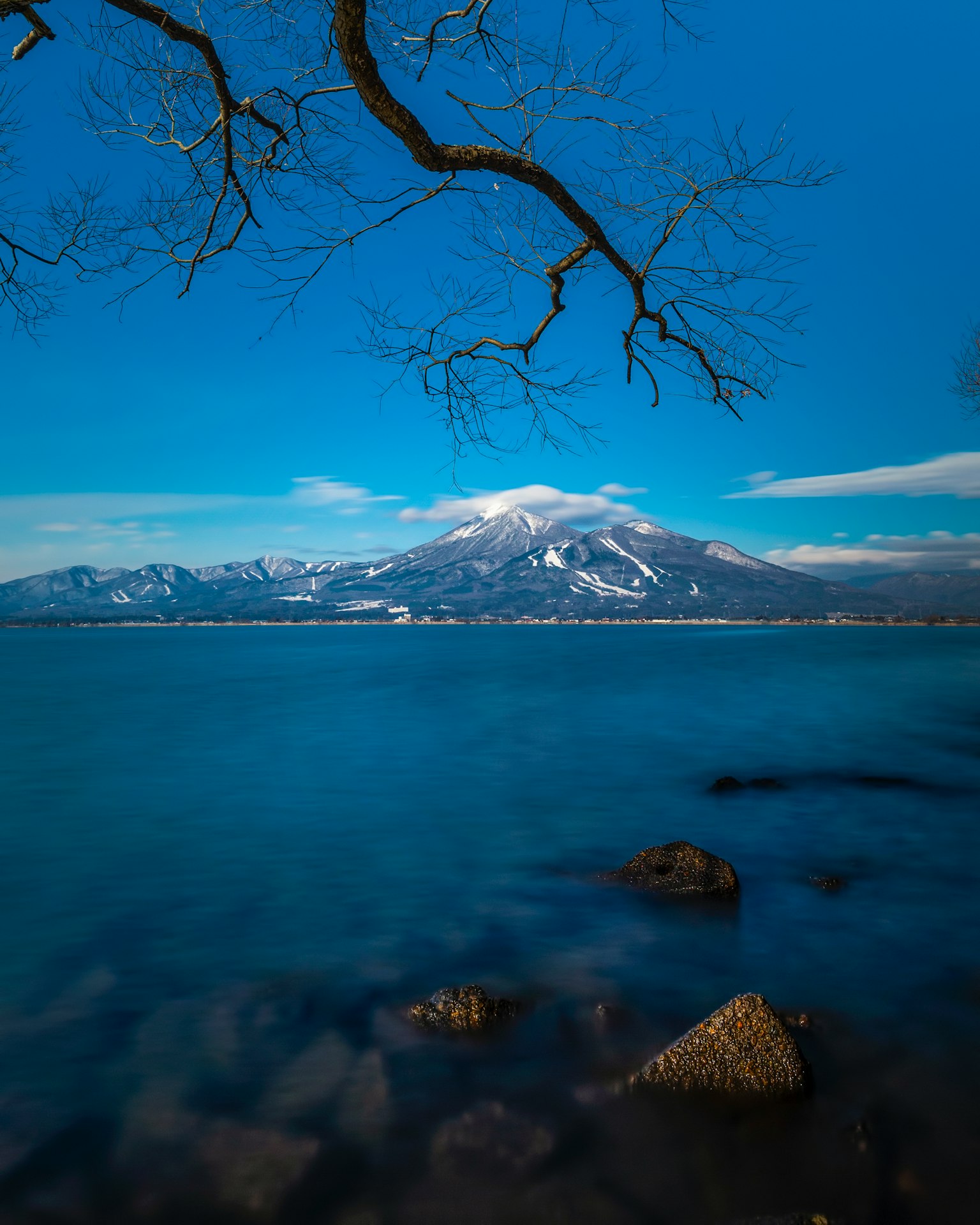 Mont enneigé sous un ciel bleu avec un lac calme