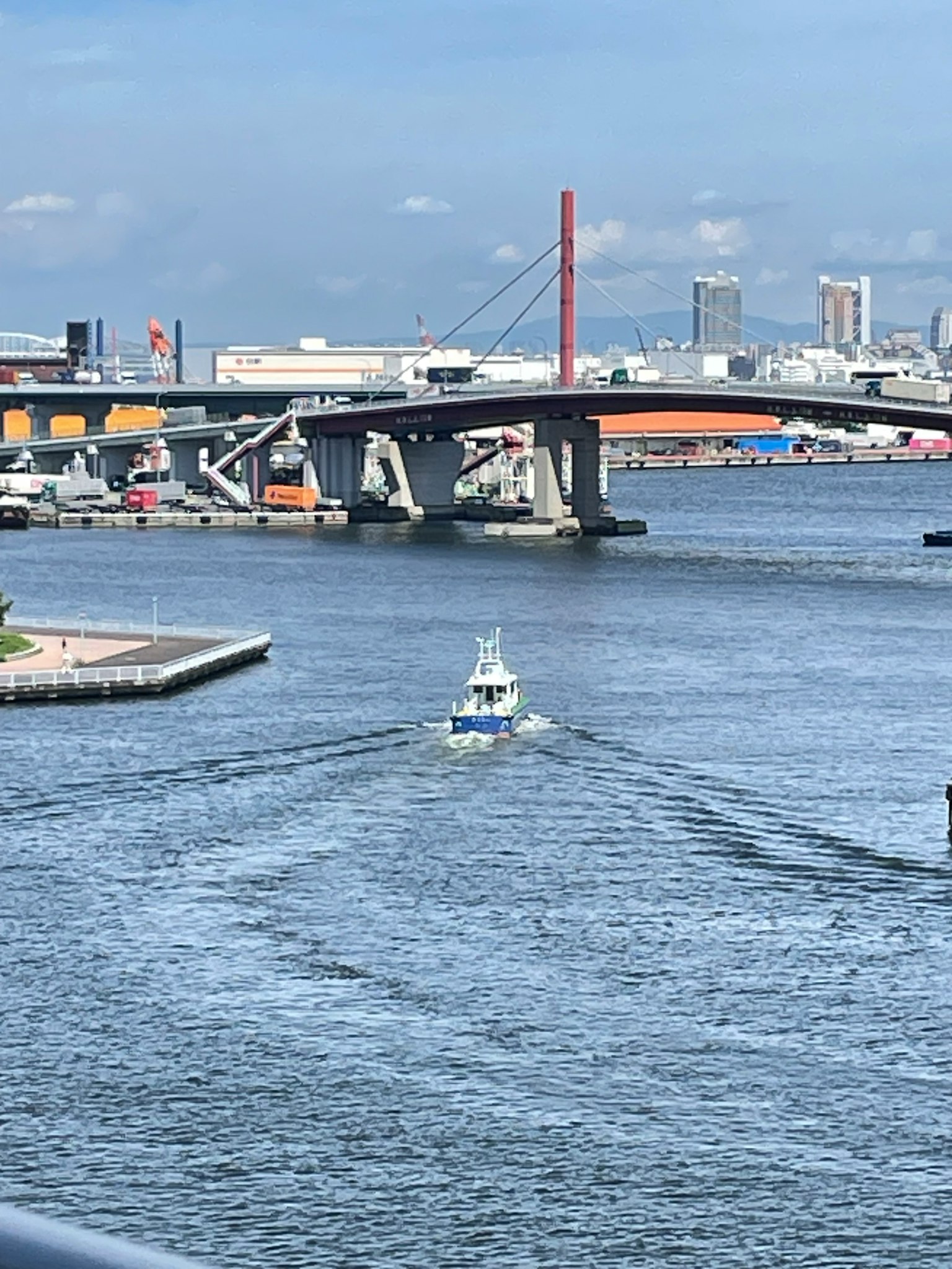 Petit bateau naviguant sur l'eau bleue avec un pont en arrière-plan