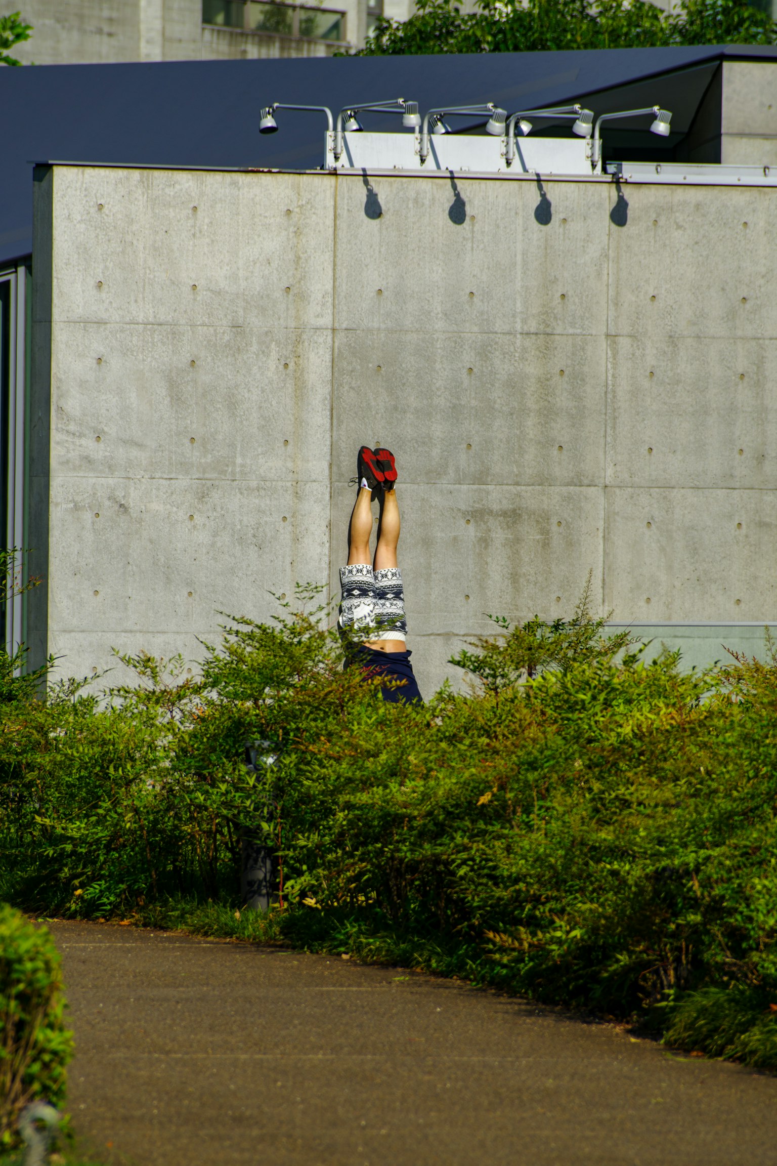 A woman doing a handstand in front of a concrete wall