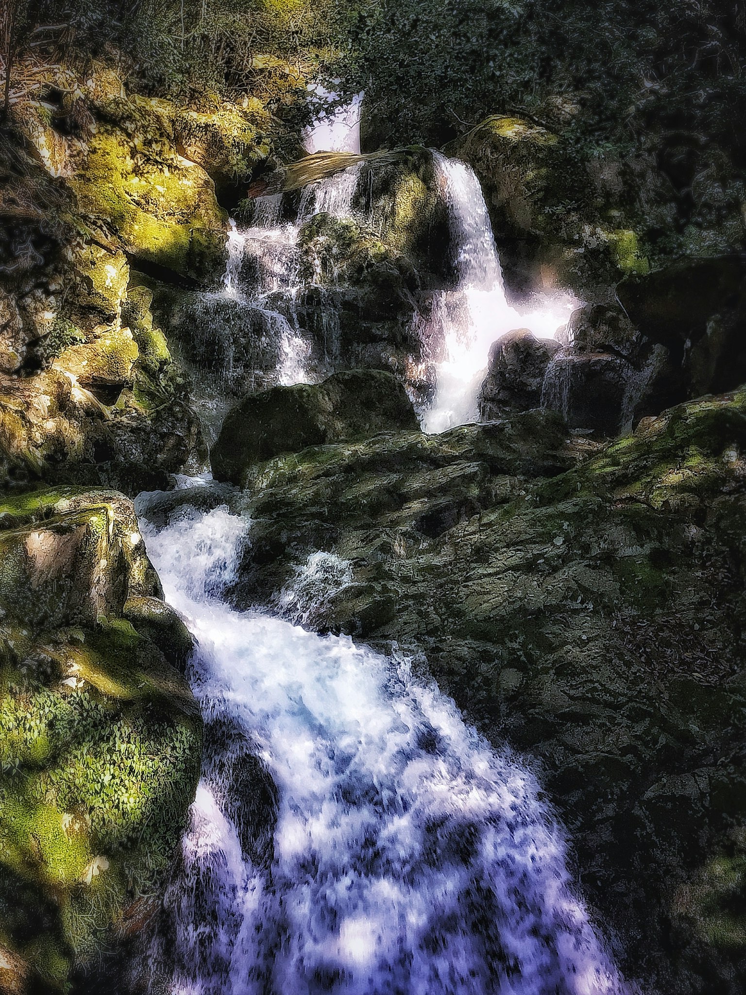 A beautiful scene of a waterfall and stream flowing between green rocks
