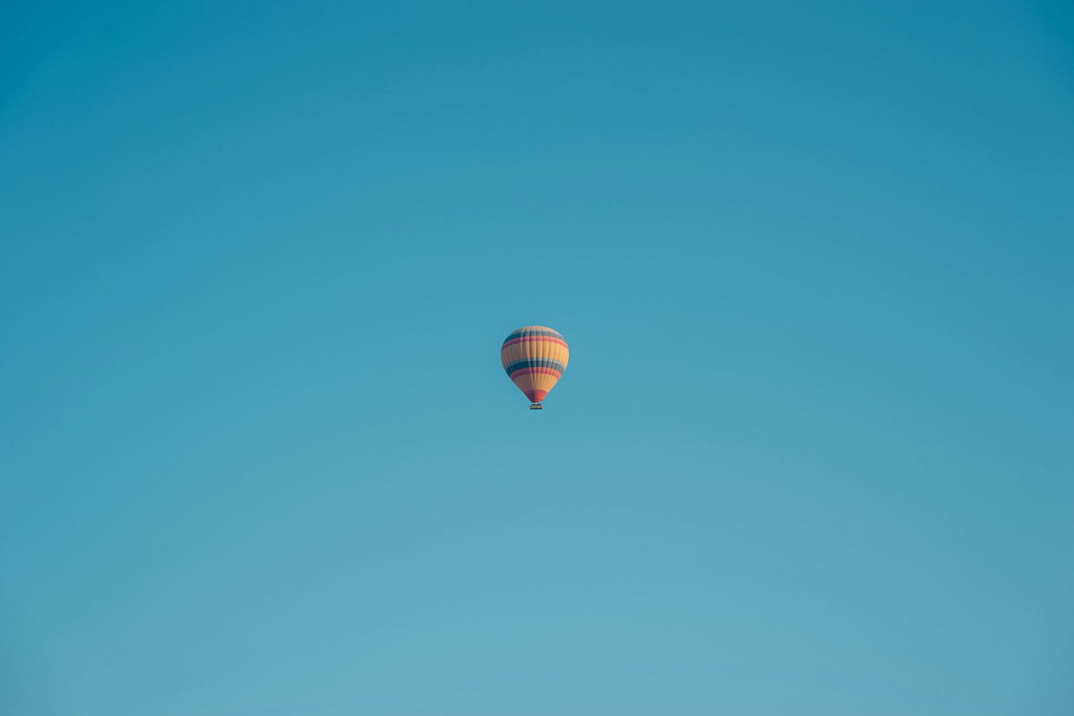 Imagen simple de un globo aerostático flotando en un cielo azul