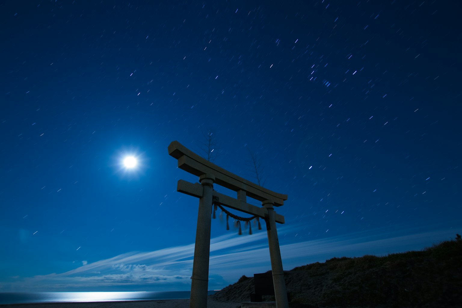 Torii-Tor unter einem hellen Mond und Sternen im Nachthimmel