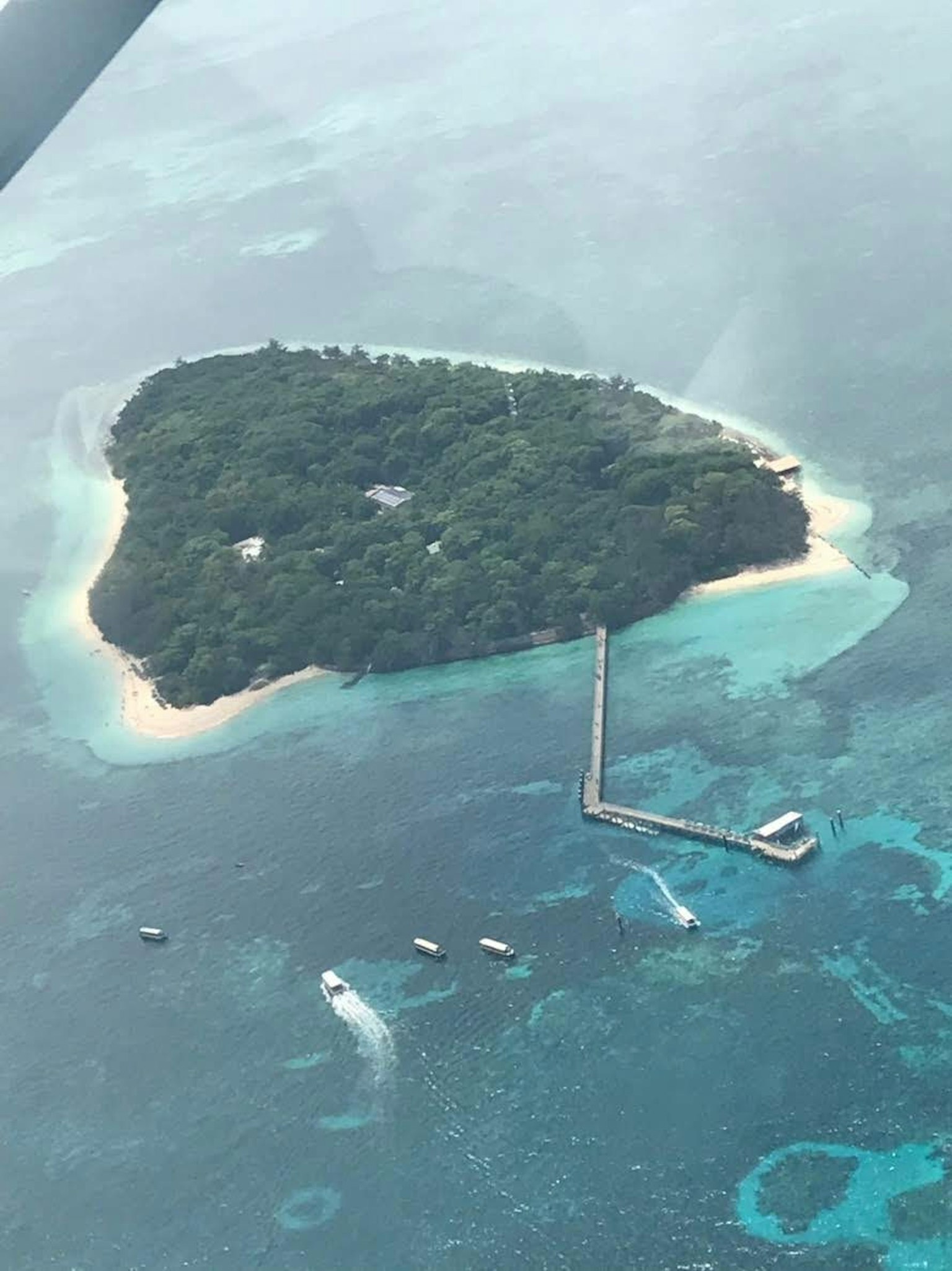 Vue aérienne d'une île verdoyante entourée d'eaux bleues avec un quai