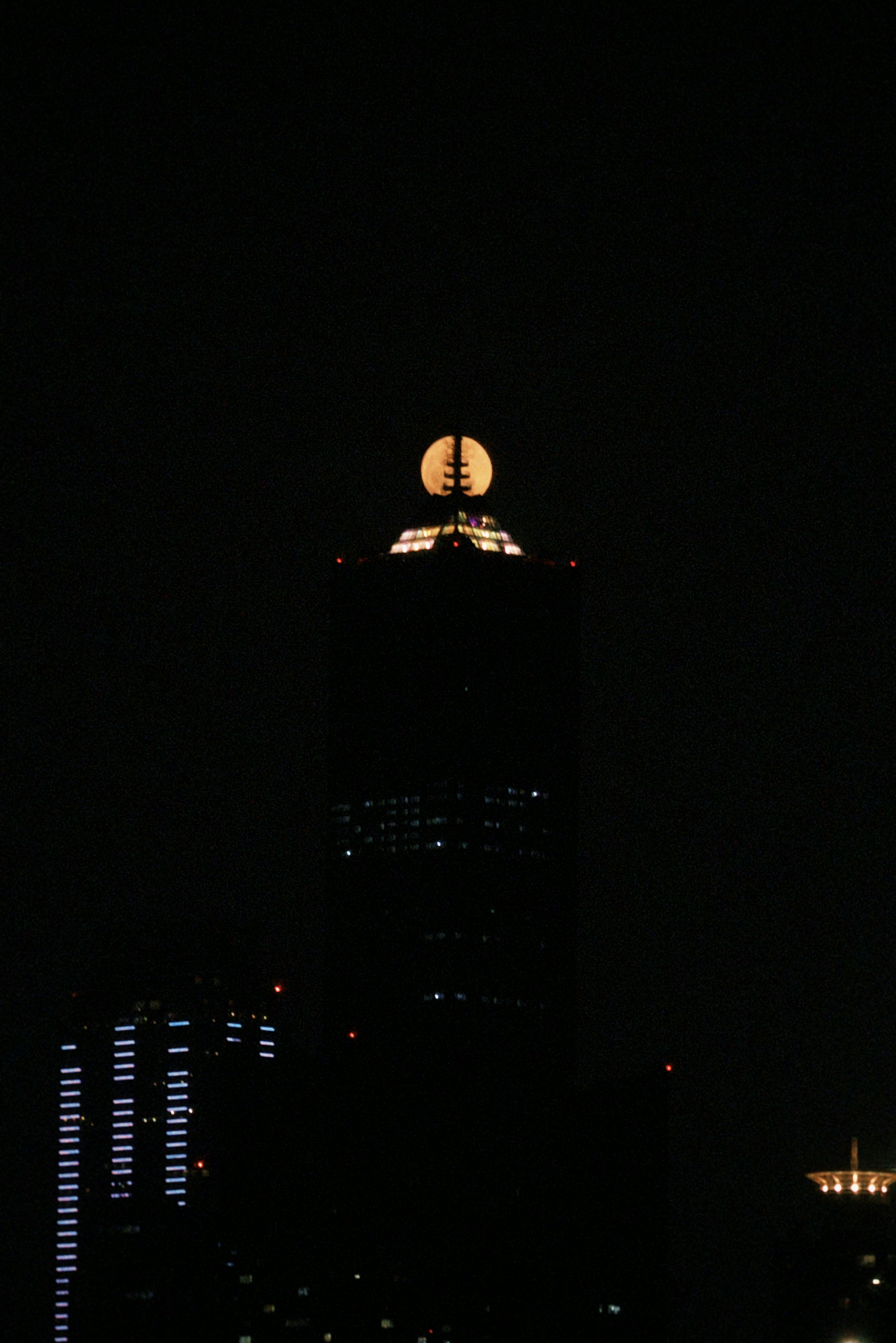 nighttime high-rise building with a glowing tower-like light